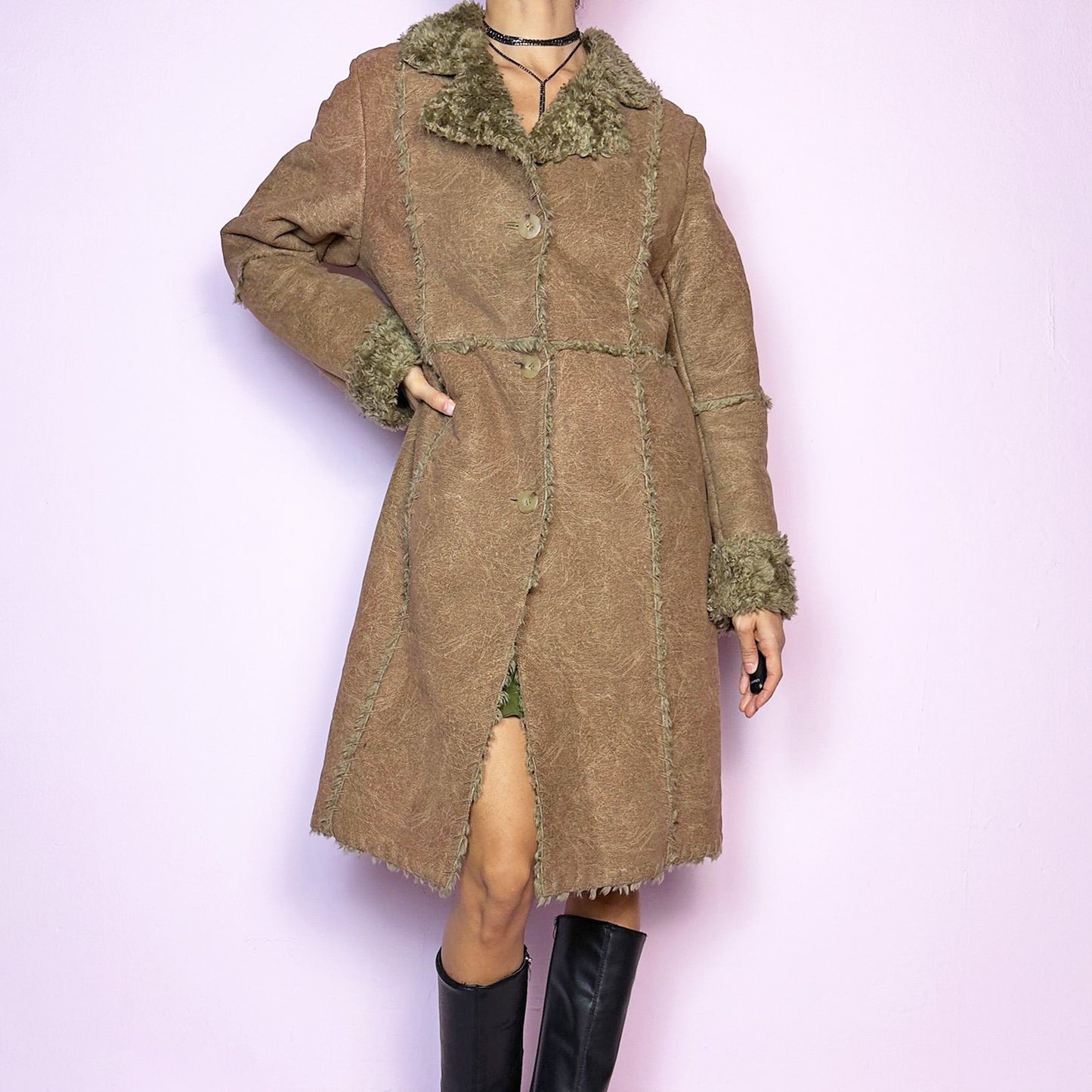 The Y2K Faux Fur Suede Long Coat is a vintage 2000s cozy piece featuring a soft brown faux suede exterior and faux shearling trim along the collar, cuffs, and seams. Its structured silhouette features button-front closure and pockets, delivering both style and warmth, perfect for autumn and winter outings. Excellent vintage condition.