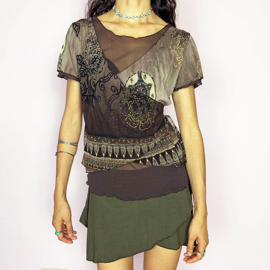 This vintage 2000s brown mesh top features an ornate floral print in gold, beige, and black with layered wrap construction. Designed with short sleeves, a scoop neckline, and fitted silhouette. Asymmetric seams and sheer texture add a deconstructed touch with boho whimsy. A rare layering piece for maximalist wardrobes or romantic alternative styling. Made from lightweight stretch polyester. Excellent vintage condition.