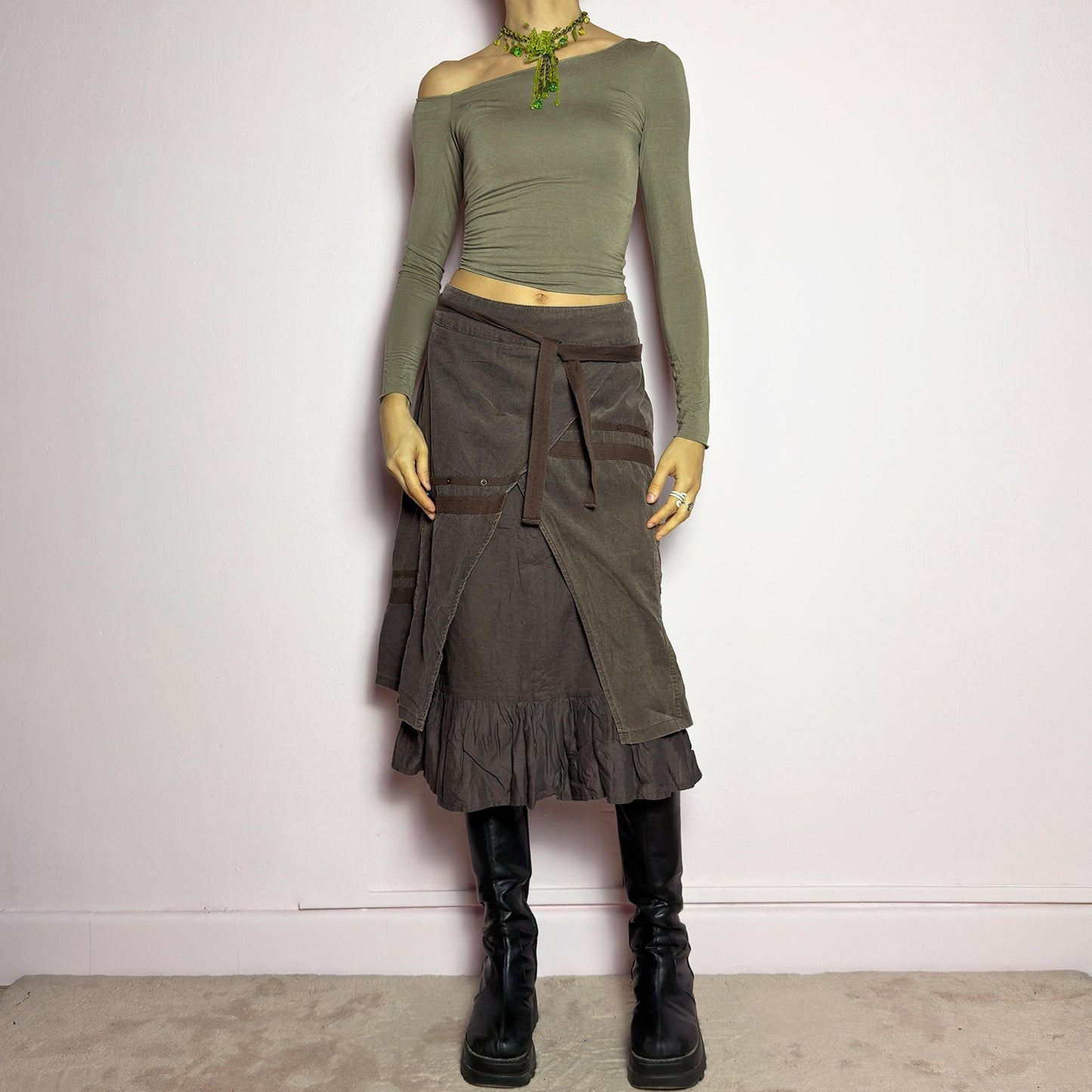 The Y2K Layered Brown Midi Skirt is a unique vintage 2000s piece featuring an asymmetric wrap design with a layered ruffle hem. Made from corduroy-cotton fabric, it includes tie closures for an adjustable fit, a back zipper closure, and subtle stitched detailing that adds a deconstructed touch. Perfect for earthy, bohemian, or avant-garde styling. adult world shop