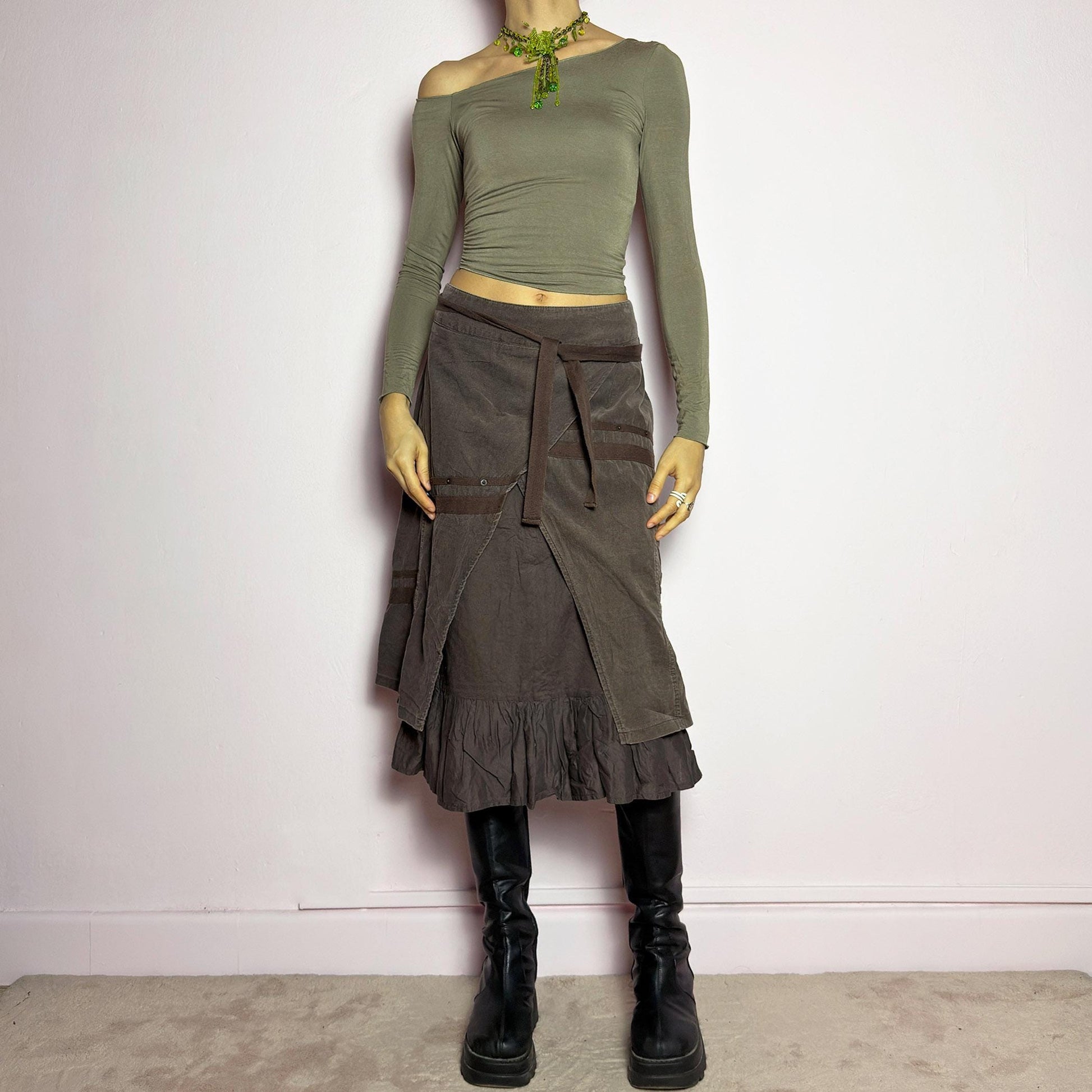 The Y2K Layered Brown Midi Skirt is a unique vintage 2000s piece featuring an asymmetric wrap design with a layered ruffle hem. Made from corduroy-cotton fabric, it includes tie closures for an adjustable fit, a back zipper closure, and subtle stitched detailing that adds a deconstructed touch. Perfect for earthy, bohemian, or avant-garde styling. adult world shop