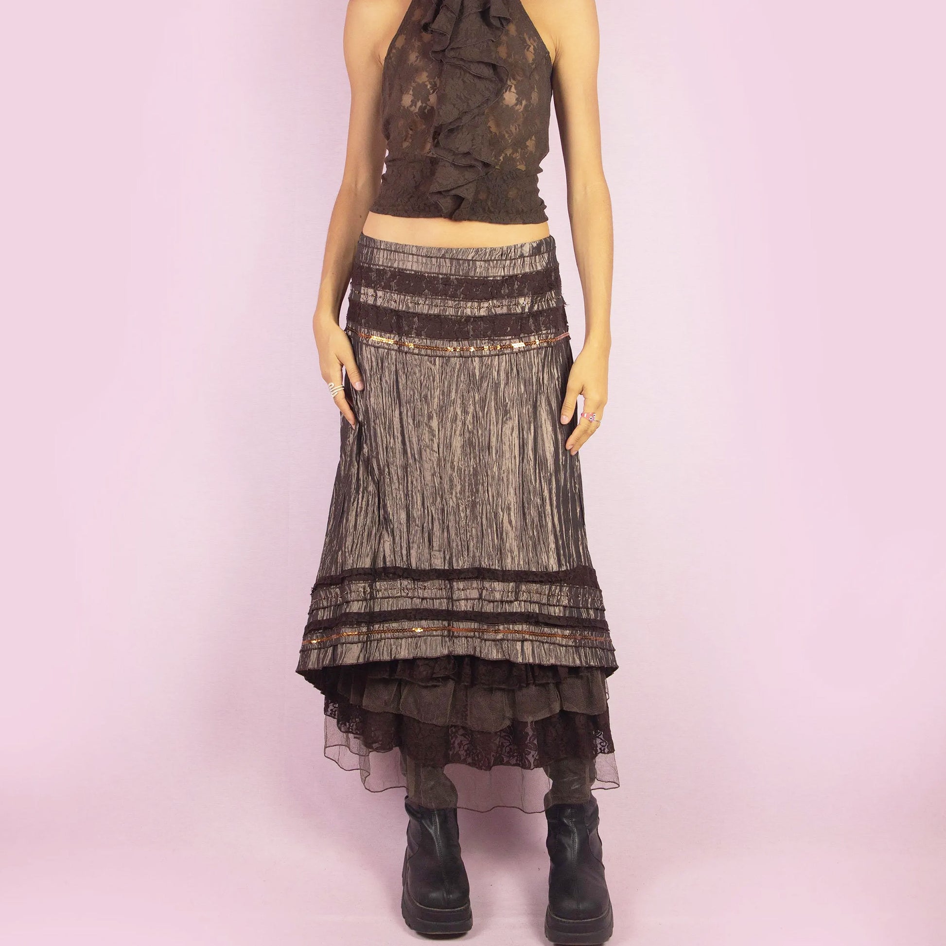 The Y2K Brown Layered Midi Skirt is a vintage 2000s piece featuring an earthy brown palette with a mix of crinkled fabric, lace, and mesh layers. The mid-waisted design and asymmetrical hemline create a flowy, bohemian silhouette, with a side zipper closure. Perfect for casual outings or whimsical evening looks.