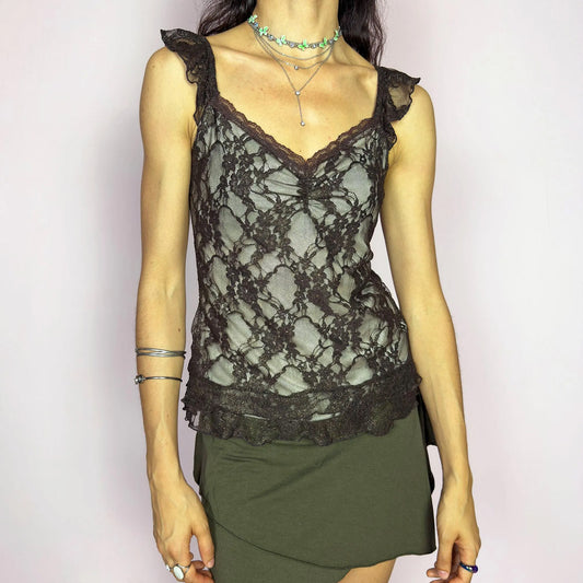 This vintage 2000s brown mesh cami top features delicate floral lace, ruched bust detail, and soft ruffle straps. The sheer, stretchy fit flatters with romantic allure, ideal for enchanting first dates, summer evening parties, or layered boho looks. A whimsical, charming, and sensual Y2K piece. Made of stretch polyester mesh. Excellent vintage condition.