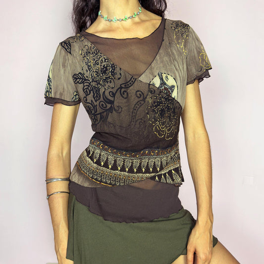 This vintage 2000s brown mesh top features an ornate floral print in gold, beige, and black with layered wrap construction. Designed with short sleeves, a scoop neckline, and fitted silhouette. Asymmetric seams and sheer texture add a deconstructed touch with boho whimsy. A rare layering piece for maximalist wardrobes or romantic alternative styling. Made from lightweight stretch polyester. Excellent vintage condition.
