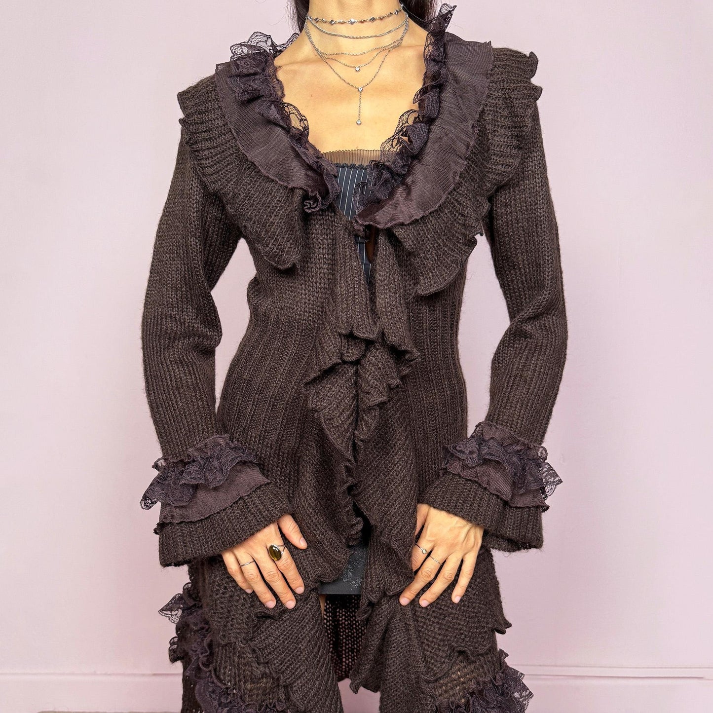 Romantic vintage 2000s dark brown longline cardigan with dramatic ruffle neckline and lace details. Features bell sleeves with ruffle cuffs, toggle front closure, and asymmetric pointy hem. Whimsical fairycore silhouette with dark baroque rococo style. Stretchy fabric for cozy winter layering. Made from acrylic mohair wool blend. Excellent vintage condition.