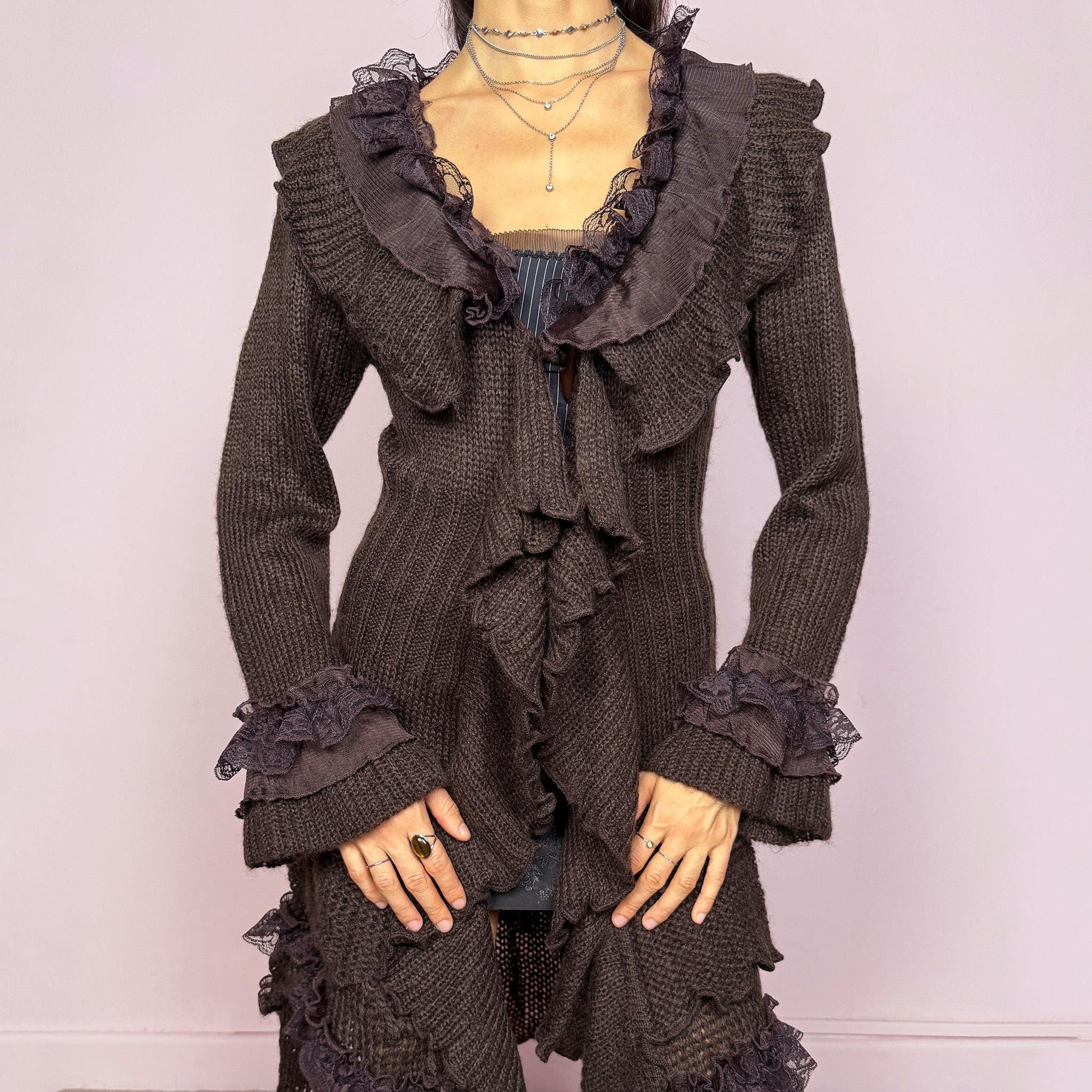 Romantic vintage 2000s dark brown longline cardigan with dramatic ruffle neckline and lace details. Features bell sleeves with ruffle cuffs, toggle front closure, and asymmetric pointy hem. Whimsical fairycore silhouette with dark baroque rococo style. Stretchy fabric for cozy winter layering. Made from acrylic mohair wool blend. Excellent vintage condition.