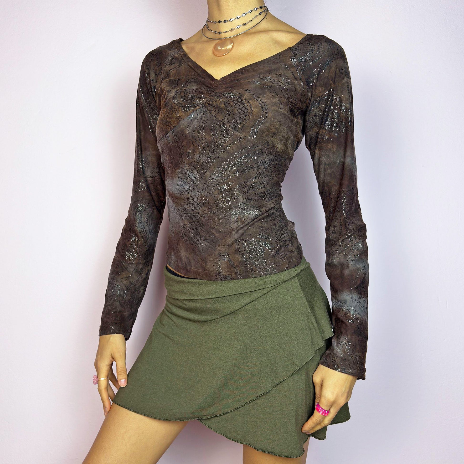 The Y2K Brown Earthy Shimmer Top is a vintage 2000s fitted and stretchy long-sleeve blouse with an earthy, abstract pattern featuring a ruched detail at the bust and subtle shimmering accents throughout. Perfect for casual outings or a night out. Great vintage condition.