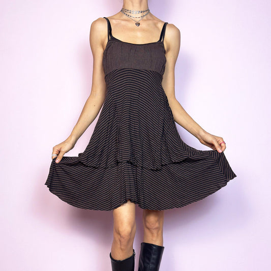 This vintage 2000s brown midi dress features a fine black stripe pattern, square neckline, and thin shoulder straps. Made from a soft, stretchy knit, it has an empire waist and a tiered asymmetric hem that drapes with ease. Perfect for summer. A casual, fairy grunge–inspired piece with subtle volume and flow—blending comfort, minimalism, and quiet edge. Great vintage condition.