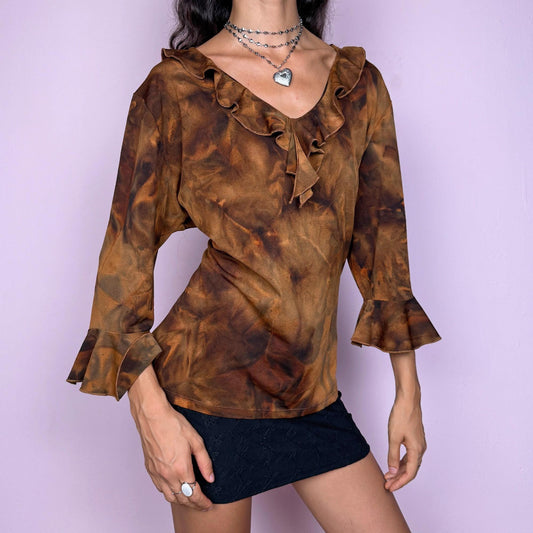 This vintage 2000s brown tie-dye top features a ruffle neckline and three-quarter bell sleeves. Made from stretchy fabric, it channels fairycore with earthy depth and whimsical structure. A perfect piece for boho layering, festival nights, or forest-inspired edits. Made in Spain from a polyester blend. Excellent vintage condition.