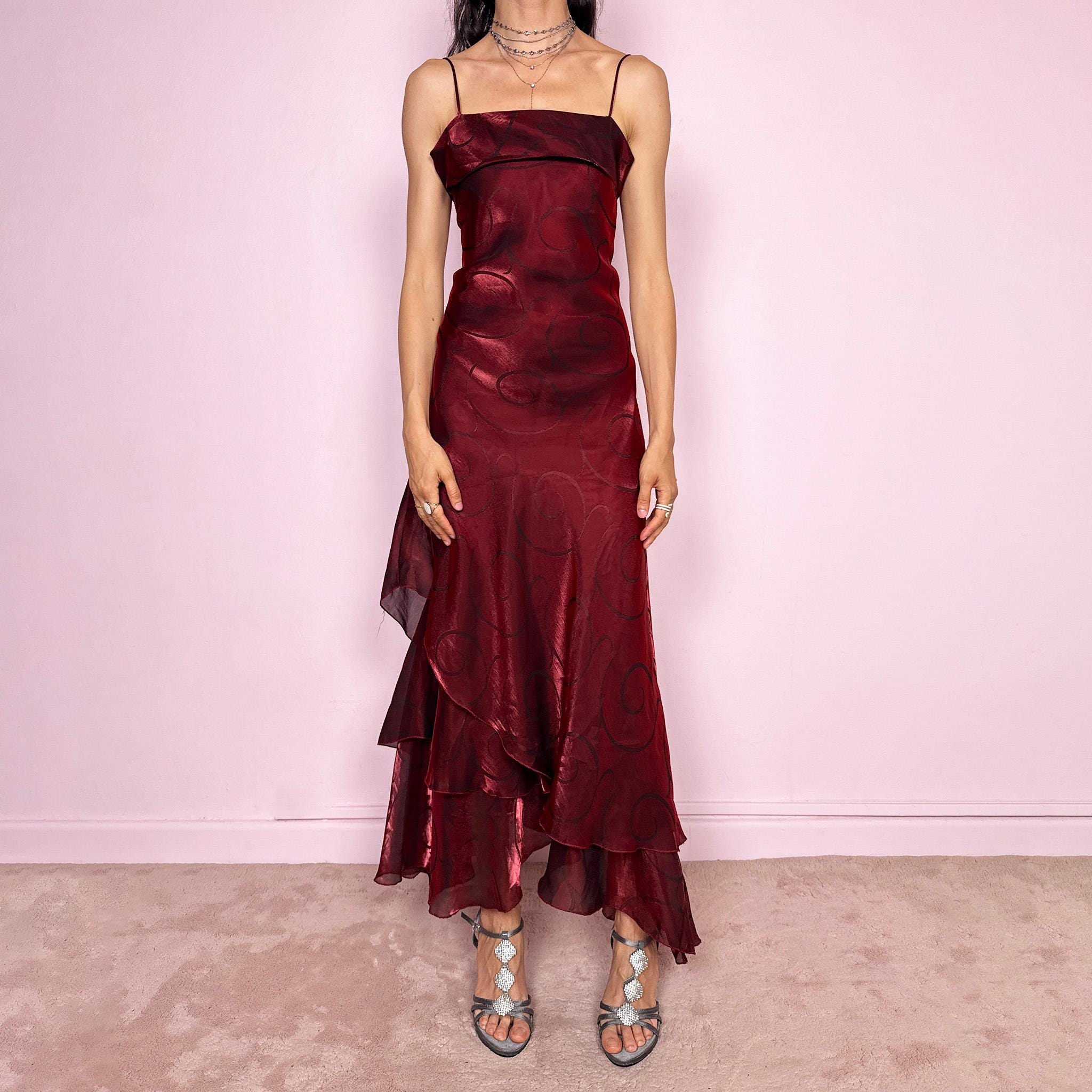Vintage 2000s statement burgundy midi dress with iridescent shimmer and elegant layered construction. Features spaghetti straps, asymmetrical tiered hem and sheer overlay with swirl pattern. Fluid body-skimming fit with romantic movement, perfect for evening events or occasionwear. Made in France from a polyester elastane blend. Excellent vintage condition.
