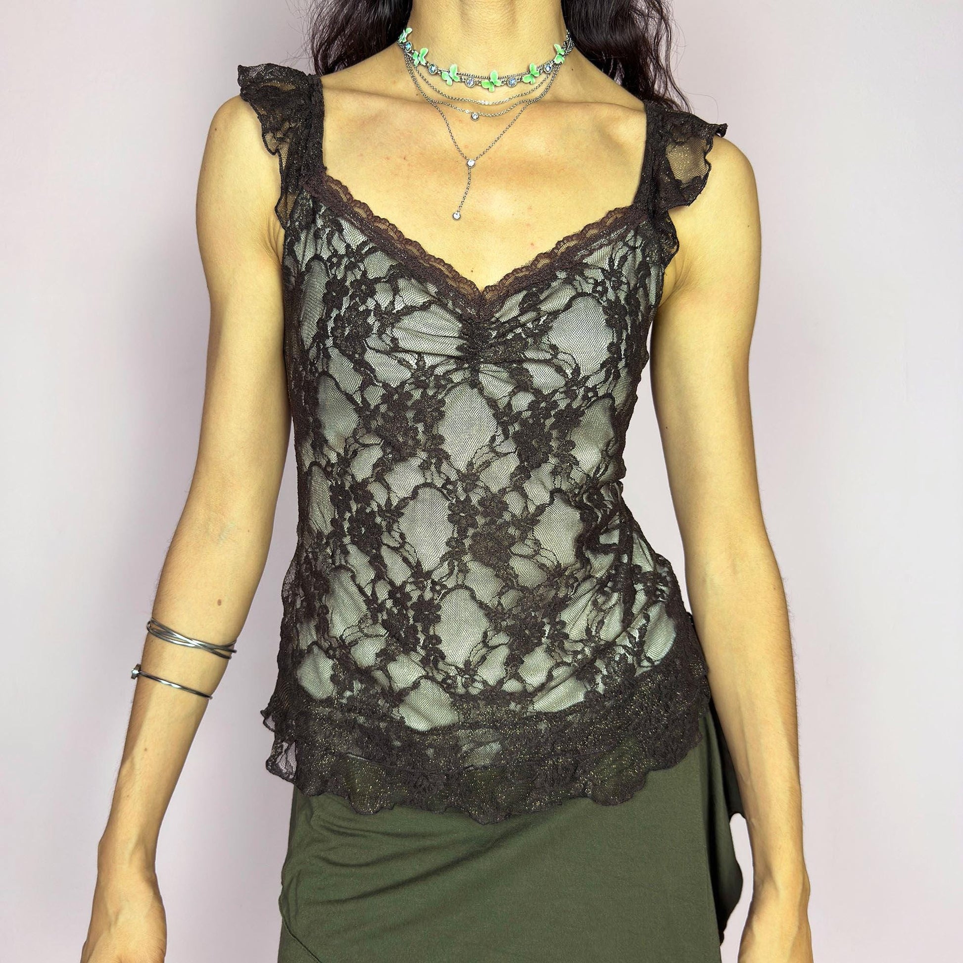 This vintage 2000s brown mesh cami top features delicate floral lace, ruched bust detail, and soft ruffle straps. The sheer, stretchy fit flatters with romantic allure, ideal for enchanting first dates, summer evening parties, or layered boho looks. A whimsical, charming, and sensual Y2K piece. Made of stretch polyester mesh. Excellent vintage condition.