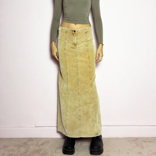 The Y2K Beige Corduroy Midi Skirt is a vintage 2000s piece featuring a soft, velvety corduroy stretchy fabric in a unique washed beige mustard tone. Designed with a flattering mid-rise fit, and a structured silhouette that flares slightly at the bottom, this skirt has a button and zipper closure. Perfect for casual and earthy outfits.