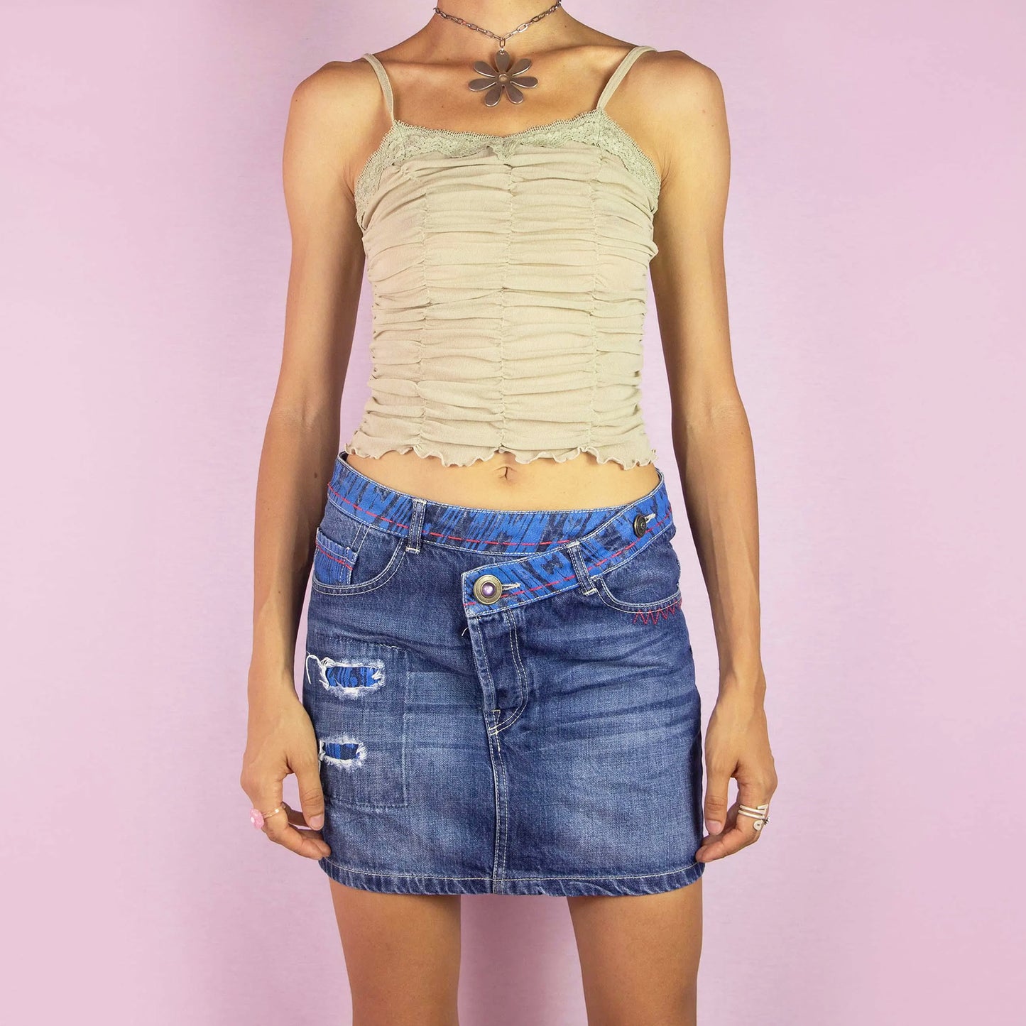 The Y2K Desigual Denim Mini Skirt is a unique vintage 2000s piece featuring a low-rise fit and a mini length silhouette. Made from medium-wash denim, this skirt has colorful contrast stitching and distressed details with fabric patches. It includes front and back pockets and a button closure. Perfect for casual wear and parties. Excellent vintage condition.