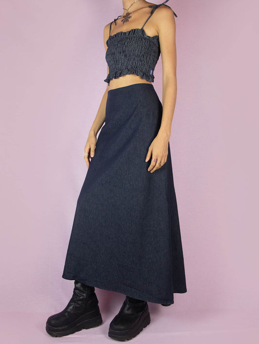 The Y2K Denim Asymmetric Maxi Skirt is a vintage 2000s piece crafted from stretchy dark-wash denim with a sleek A-line silhouette. Featuring a unique asymmetric cut and a back zipper closure. Perfect for avant-garde styling or subversive casual looks, this skirt brings refined structure to minimalist summer outfits and transitional fall layers.