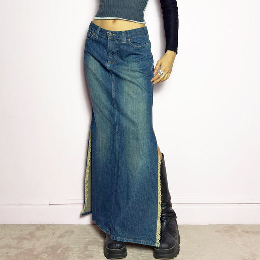 The Y2K Denim Side Slit Maxi Skirt is a vintage 2000s statement piece featuring a structured mid-rise fit and a sleek, elongated silhouette. Designed with frayed side slit details, a button and zipper closure, and classic five-pocket styling, this skirt is perfect for casual streetwear looks.