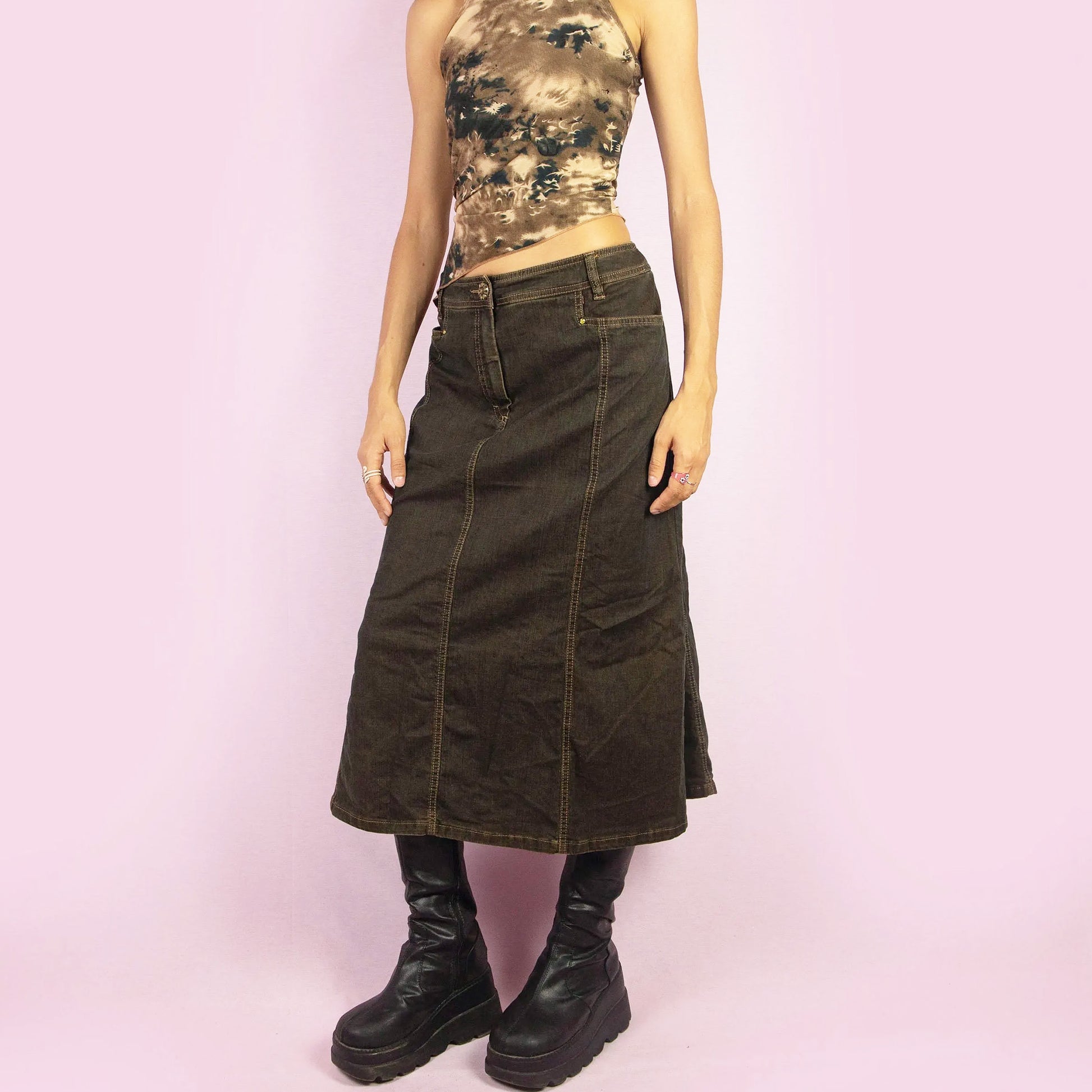 The Y2K Denim Flare Midi Skirt is a vintage 2000s piece featuring a mid-rise fit and a slightly flared silhouette. With a dark denim finish, this skirt has a front zipper closure and pockets. Perfect for casual autumn outfits or night events.