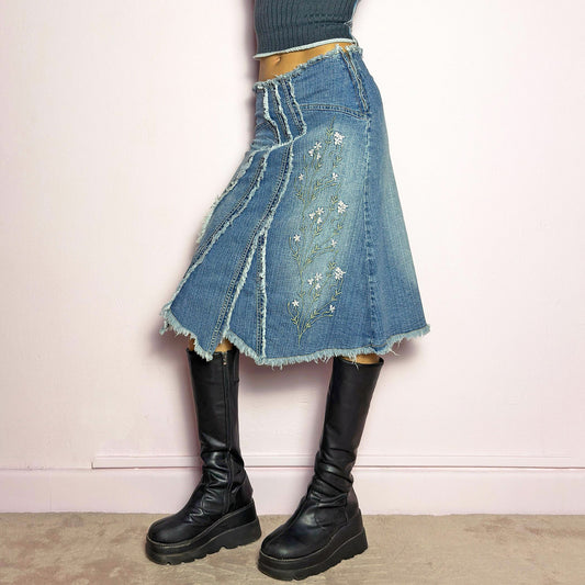 The Y2K Denim Patchwork Midi Skirt is a vintage 2000s statement piece featuring a deconstructed patchwork denim design with raw frayed edges, a panel construction that creates a flared silhouette and delicate floral embroidery. Finished with a high-waisted fit, asymmetrical hem, and a side zipper closure, this skirt is perfect for fairy grunge, bohemian, and eclectic outfits. Excellent vintage condition.
