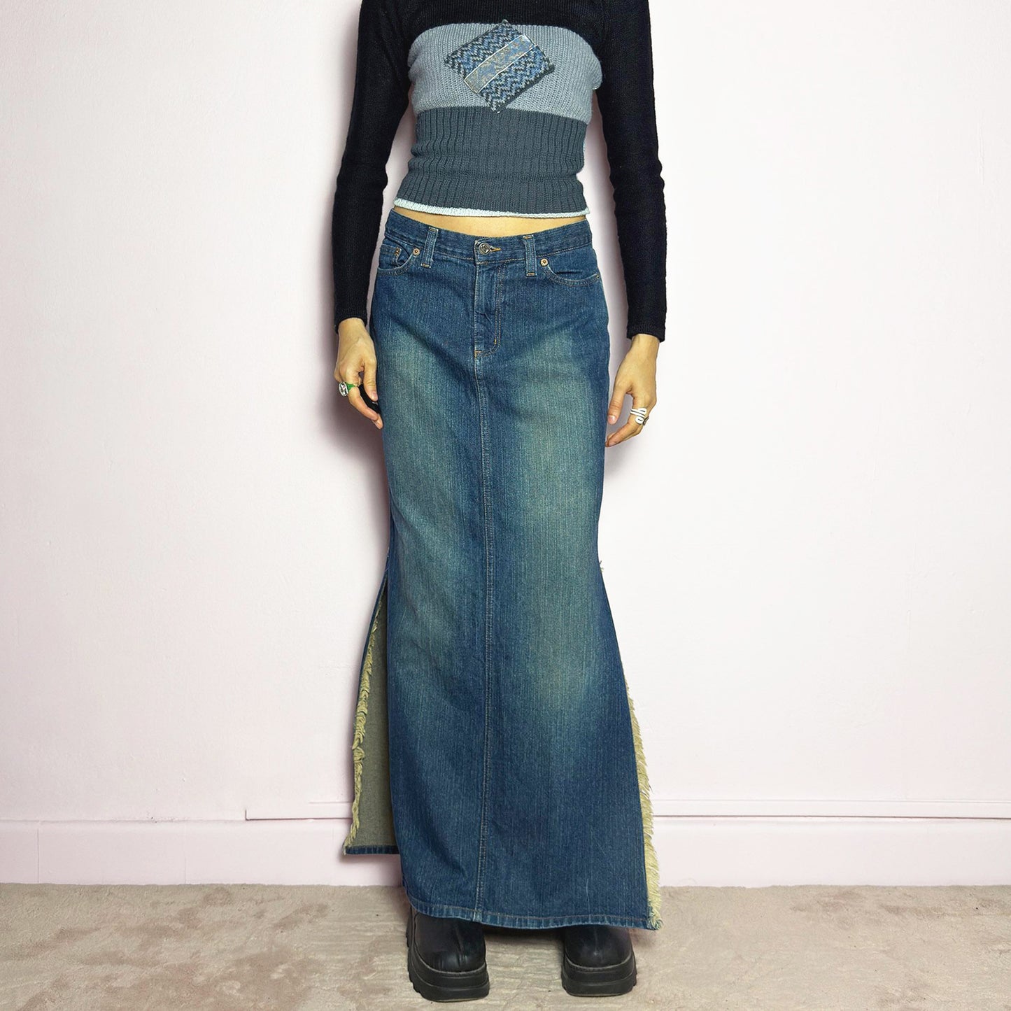 The Y2K Denim Side Slit Maxi Skirt is a vintage 2000s statement piece featuring a structured mid-rise fit and a sleek, elongated silhouette. Designed with frayed side slit details, a button and zipper closure, and classic five-pocket styling, this skirt is perfect for casual streetwear looks. Excellent vintage condition.