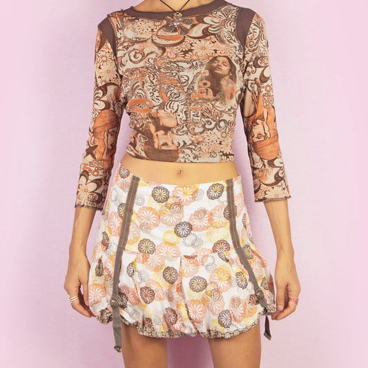 The Y2K Floral Bubble Mini Skirt is a vintage 2000s piece featuring a playful floral print in shades of orange, yellow, and brown. Designed with a distinctive bubble silhouette, it includes adjustable side drawstrings for added shape and style, along with a side zipper closure. The lightweight cotton fabric and unique details give this skirt a fun vibe, making it perfect for casual summer looks.