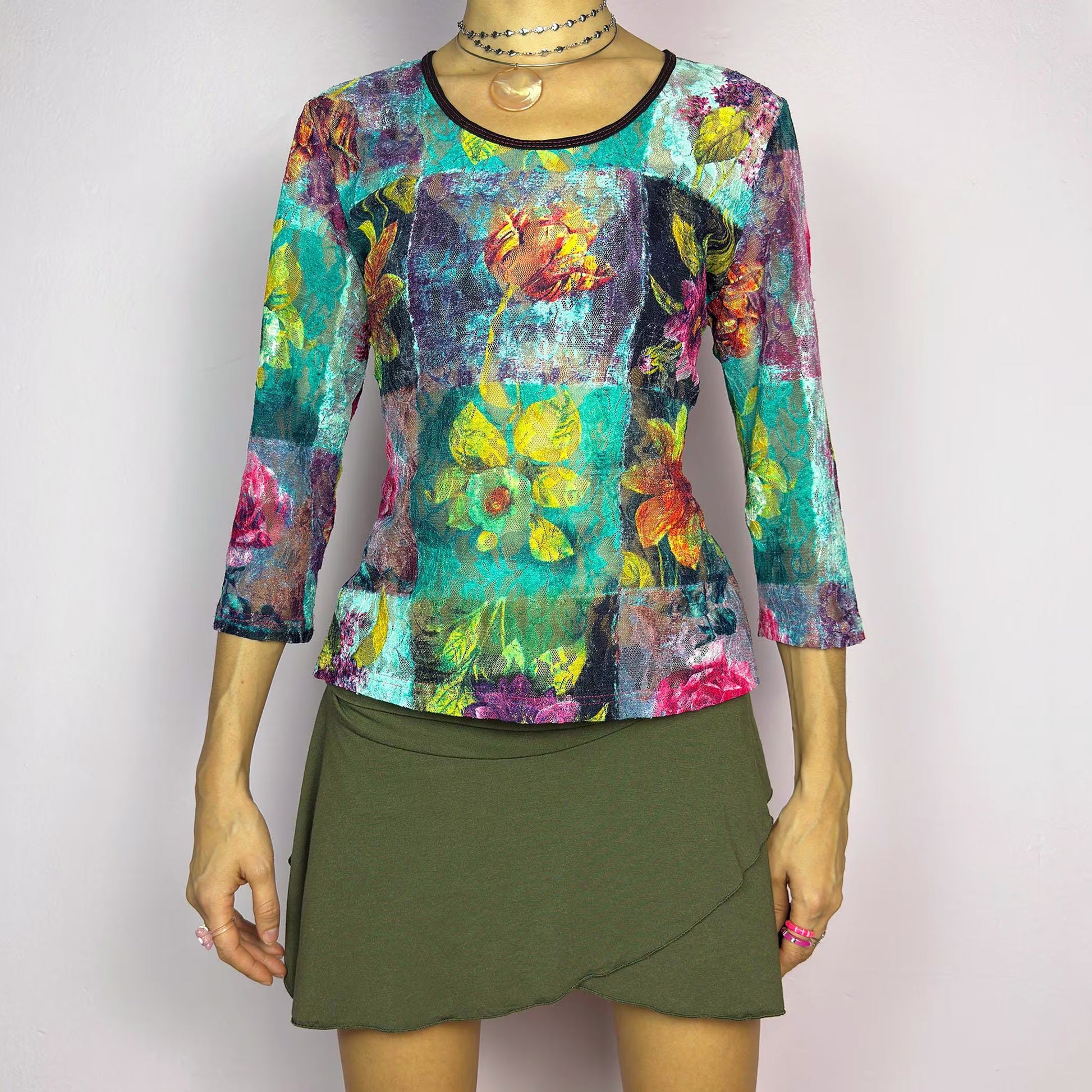 The Y2K Painting Lace Mesh Top is a vintage 2000s artistic statement piece. Featuring a semi-sheer lace fabric adorned with a bold, vibrant floral pattern resembling a painterly masterpiece, a scoop neckline and 3/4 sleeves. Perfect for layering in spring or summer. Excellent vintage condition.