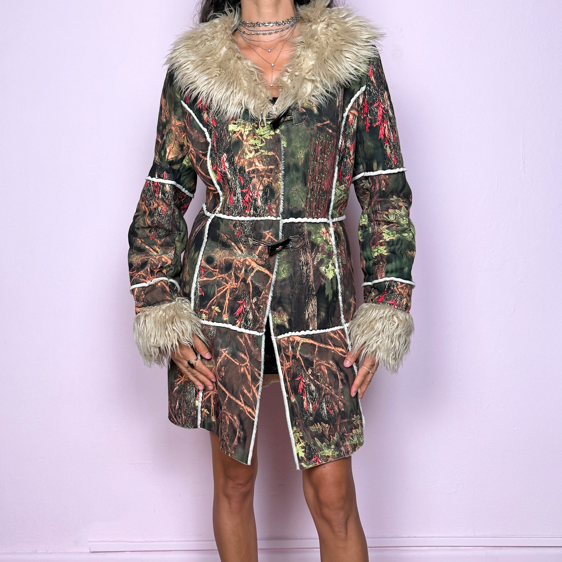 This vintage 2000s Penny Lane coat features a surreal forest graphic print in earthy greens, browns, and red tones, trimmed with plush beige faux fur at the collar and cuffs. Designed with toggle closures, contrast seams and pockets, it evokes fairycore and woodland Y2K energy with bohemian allure. Cozy yet bold, perfect for winter layering and statement street styling. A collectible archive outerwear piece. Made from warm polyester blend. Excellent vintage condition.
