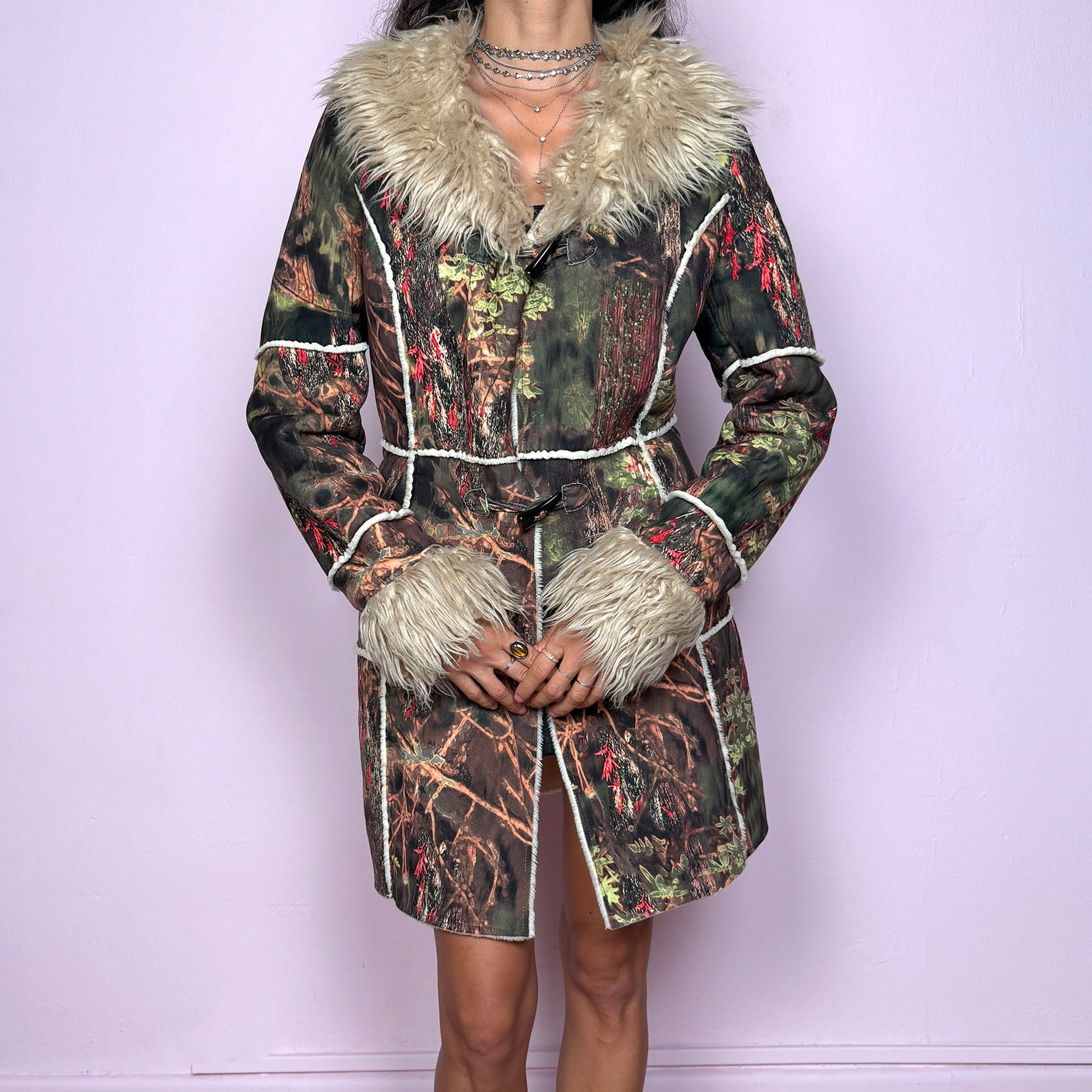 This vintage 2000s Penny Lane coat features a surreal forest graphic print in earthy greens, browns, and red tones, trimmed with plush beige faux fur at the collar and cuffs. Designed with toggle closures, contrast seams and pockets, it evokes fairycore and woodland Y2K energy with bohemian allure. Cozy yet bold, perfect for winter layering and statement street styling. A collectible archive outerwear piece. Made from warm polyester blend. Excellent vintage condition.