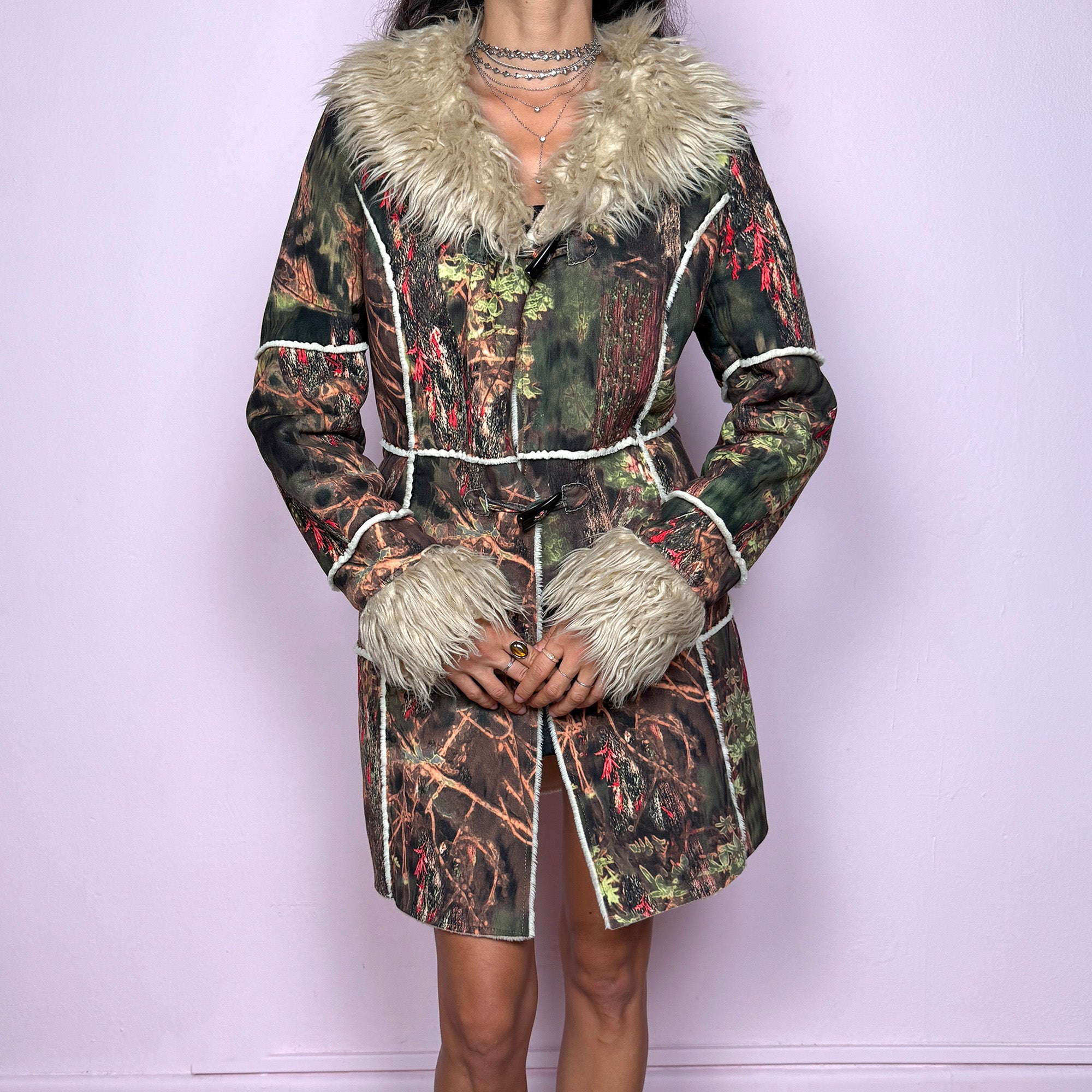 This vintage 2000s Penny Lane coat features a surreal forest graphic print in earthy greens, browns, and red tones, trimmed with plush beige faux fur at the collar and cuffs. Designed with toggle closures, contrast seams and pockets, it evokes fairycore and woodland Y2K energy with bohemian allure. Cozy yet bold, perfect for winter layering and statement street styling. A collectible archive outerwear piece. Made from warm polyester blend. Excellent vintage condition.