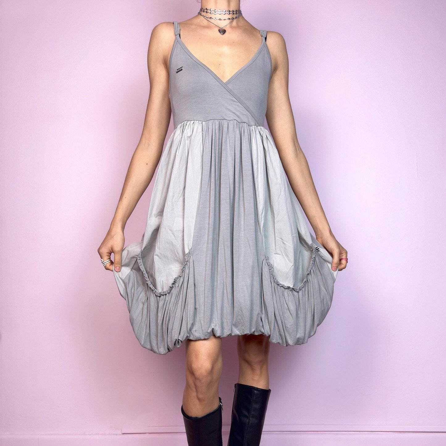 This vintage 2000s mini dress features a soft grey palette, deep wrap V-neckline, and empire waist with adjustable straps and light stretch. The voluminous bubble hem and oversized ruched pockets create sculptural movement and playful volume. Perfect for summer. A cyber-futuristic, deconstructed silhouette—airy, offbeat, and effortlessly cool. Excellent vintage condition.