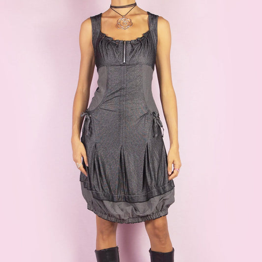 The Y2K Gray Bubble Mini Dress is a vintage 2000s piece featuring a striped, stretchy fabric with a structured bodice and a front zipper detail. The design includes pockets with drawstrings and the bubble hemline adds volume and playfulness. Perfect for night outings or unique casual styles. Great vintage condition.