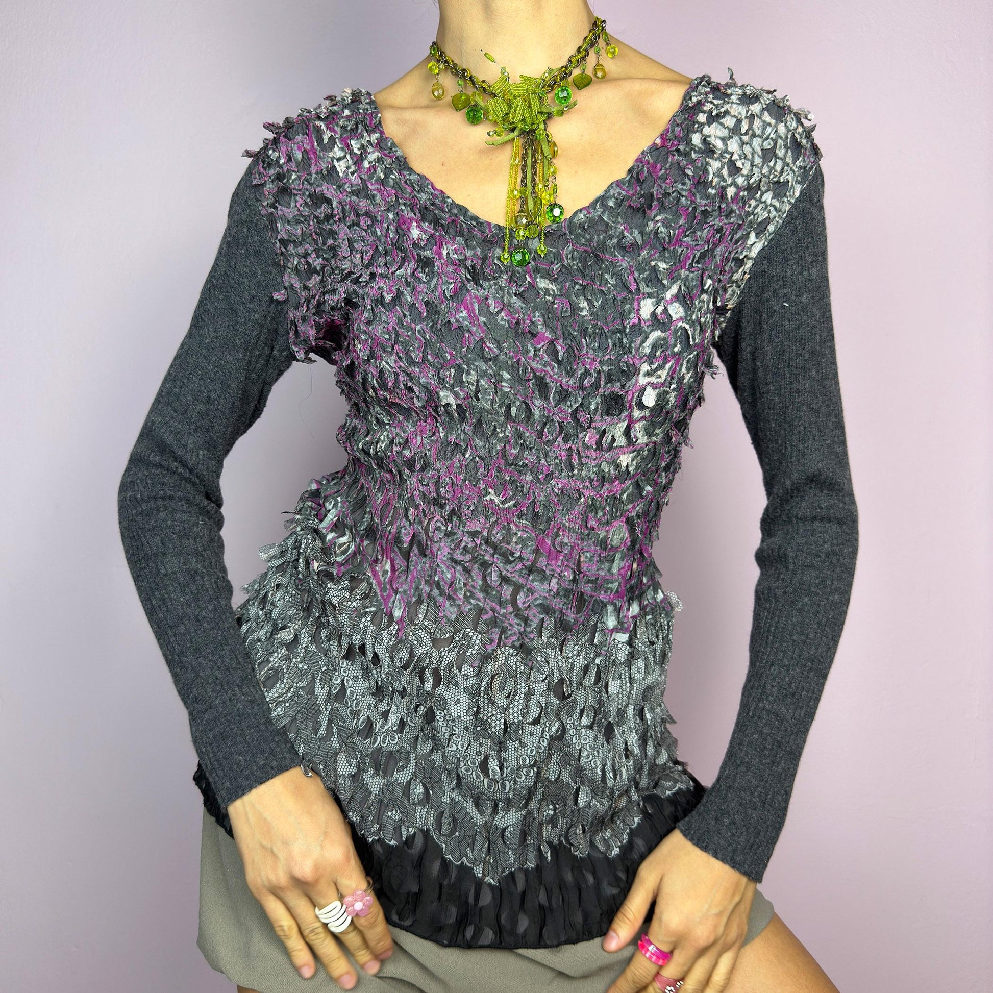 The Y2K Gray Crinkled Textured Top is a vintage 2000s piece by designer Roberto Verino, featuring a unique sheer overlay with delicate cut-out details that create a dimensional, deconstructed look. The long knit sleeves contrast beautifully with the intricate textures, adding depth to this stretchy fit design. A standout piece for those who love avant-garde fashion. adult world shop