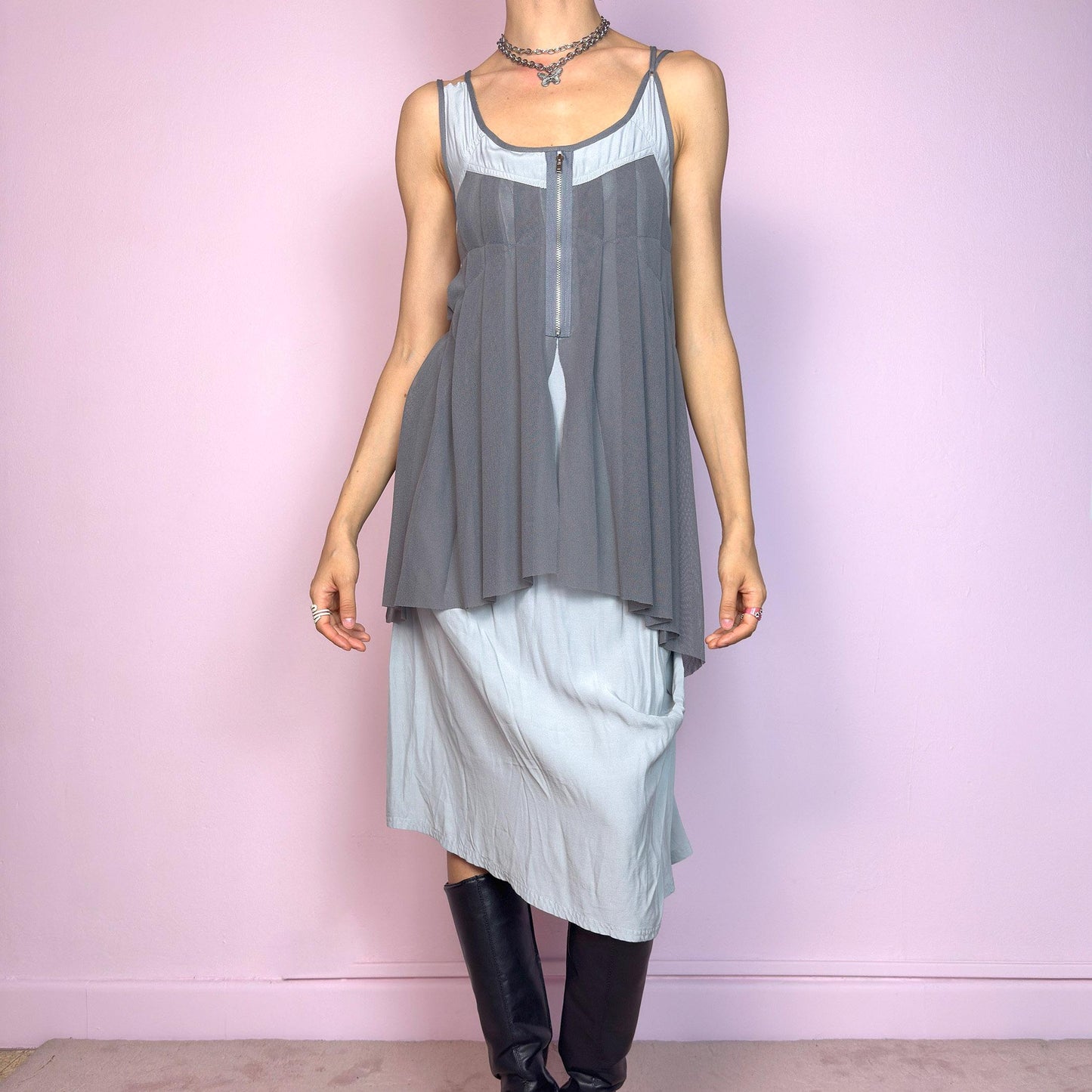This vintage 2000s midi dress features layered grey tones in mixed textures, including a pleated mesh overlay with faux front zip detail and a side zipper closure. The sleeveless cut and flared asymmetric drape create sculptural movement. Falls below the knee, lightweight, with no stretch. A deconstructed Y2K silhouette—futuristic, quiet, and avant-garde. Perfect for summer days or experimental night looks. Excellent vintage condition.