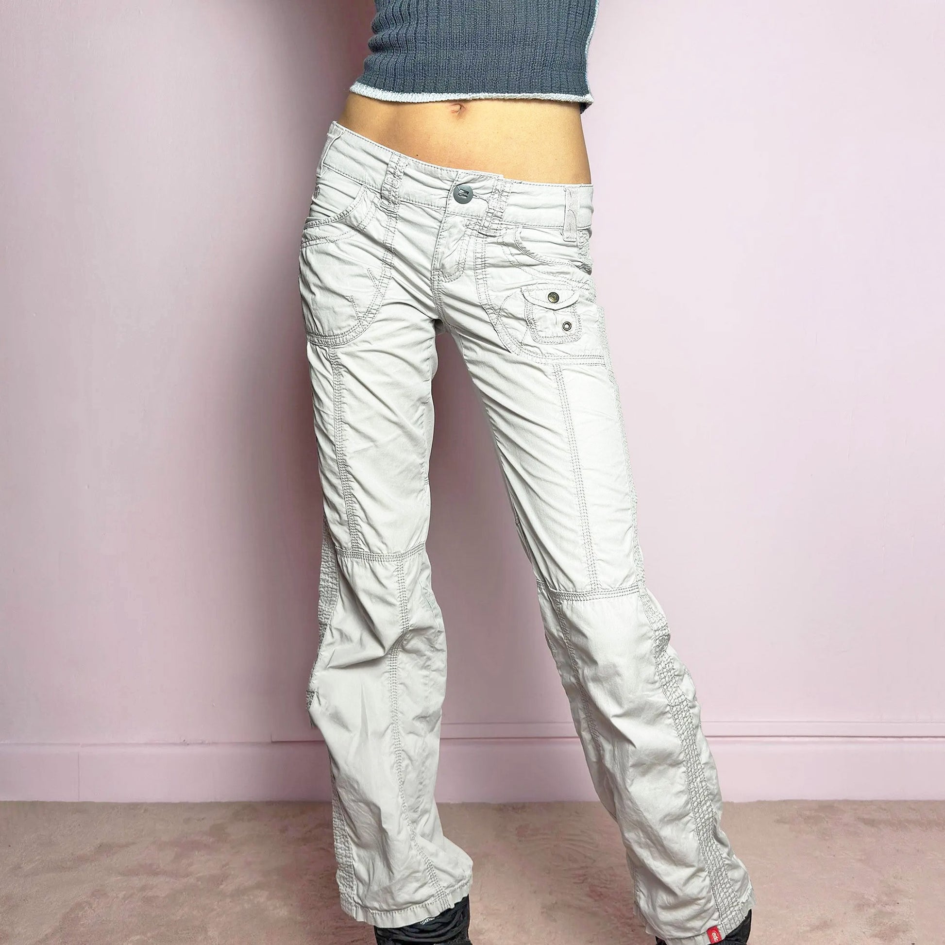 The Y2K Gray Low-Rise Pants are a vintage 2000s piece featuring a lightweight, structured fabric with a washed gray tone. Designed with a low-rise waist, button and zipper closure, and pockets, these pants offer a cropped, relaxed straight-leg fit with contrast stitching and panel detailing for a utilitarian-inspired aesthetic. Perfect for streetwear and casual grunge looks.