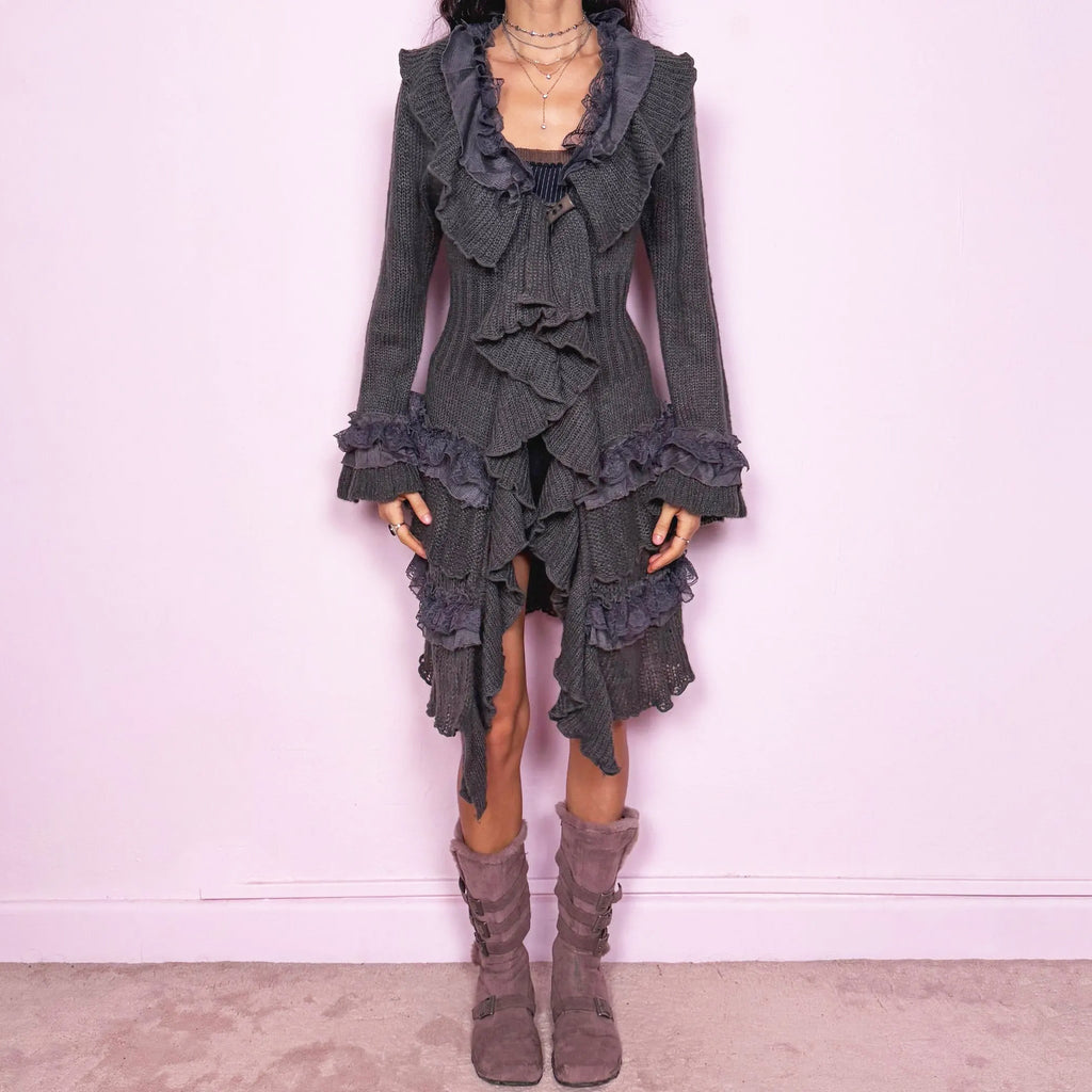 Romantic vintage 2000s gray longline cardigan with dramatic ruffle neckline and lace details. Features bell sleeves with ruffle cuffs, toggle front closure, and asymmetric pointy hem. Whimsical fairycore silhouette with dark baroque rococo style. Stretchy fabric for cozy winter layering. Made from a 35% mohair and 45% acrylic blend. Excellent vintage condition.