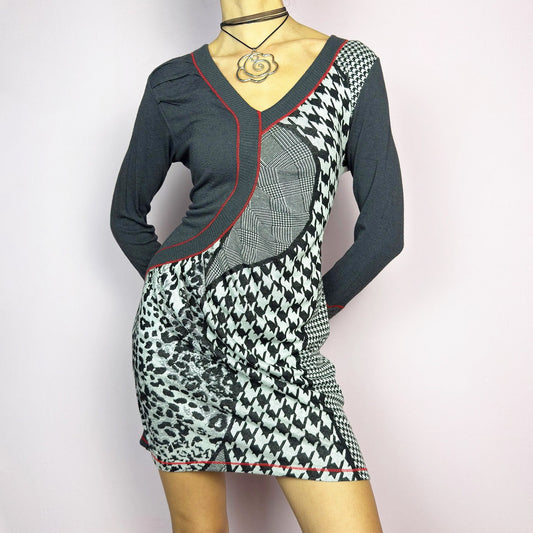 The Y2K Gray Patchwork Mini Dress is a vintage 2000s piece featuring a bold patchwork print with a mix of houndstooth, plaid, and leopard patterns, a V-neckline and long sleeves. The fitted silhouette is accentuated with contrast red stitching. Made from a stretchy fabric, it offers a flattering fit. Ideal for casual streetwear or a night-out ensemble. Excellent vintage condition.