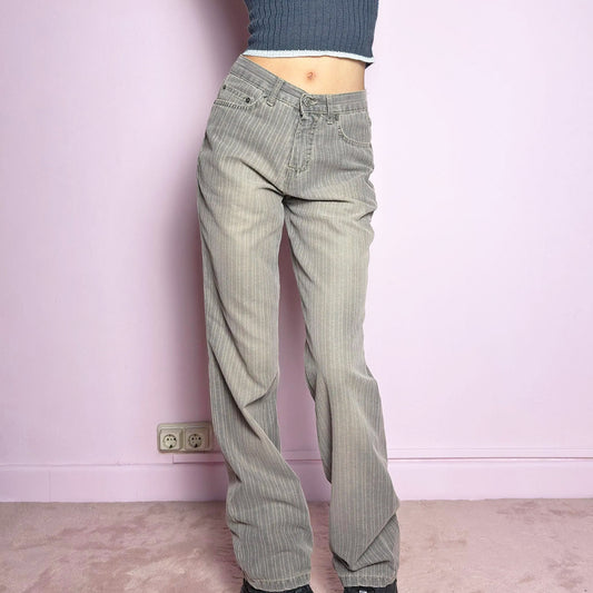 The Y2K Gray Straight Jeans are a vintage 2000s essential featuring a structured fabric with subtle pinstripes. Designed with a relaxed straight-leg fit, a flattering high waist, button and zipper closure, and pockets, these jeans offer a sleek yet effortless silhouette. Perfect for casual outfits.