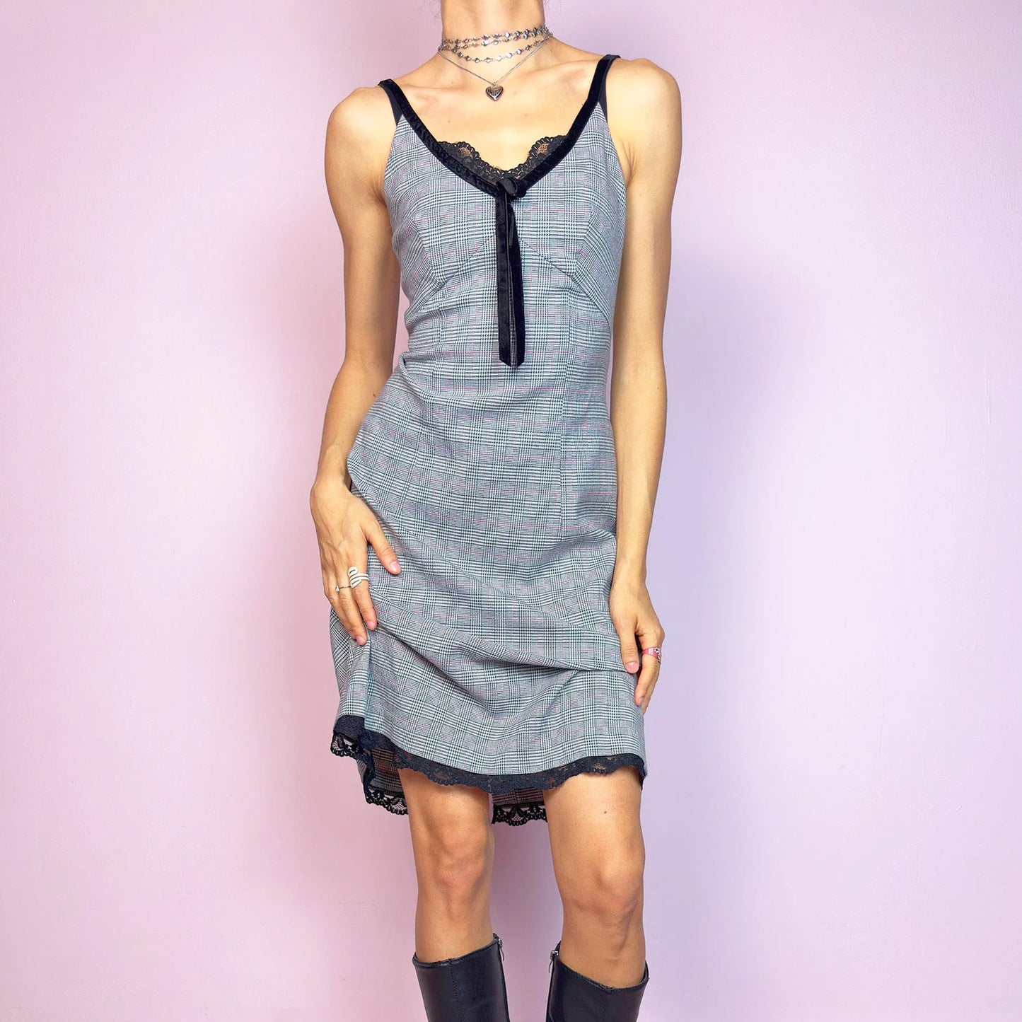 This vintage 2000s slip dress features a gray plaid print with black lace trim and a velvet bow at the bust. It has adjustable straps, a hidden back zipper, mid-length hem, and subtle stretch. The lingerie-inspired cut blends romantic and preppy codes, perfect for summer or layered transitions. A sleek office-core silhouette with soft edge—equal parts elegance and vintage 2000s attitude. Excellent vintage condition.