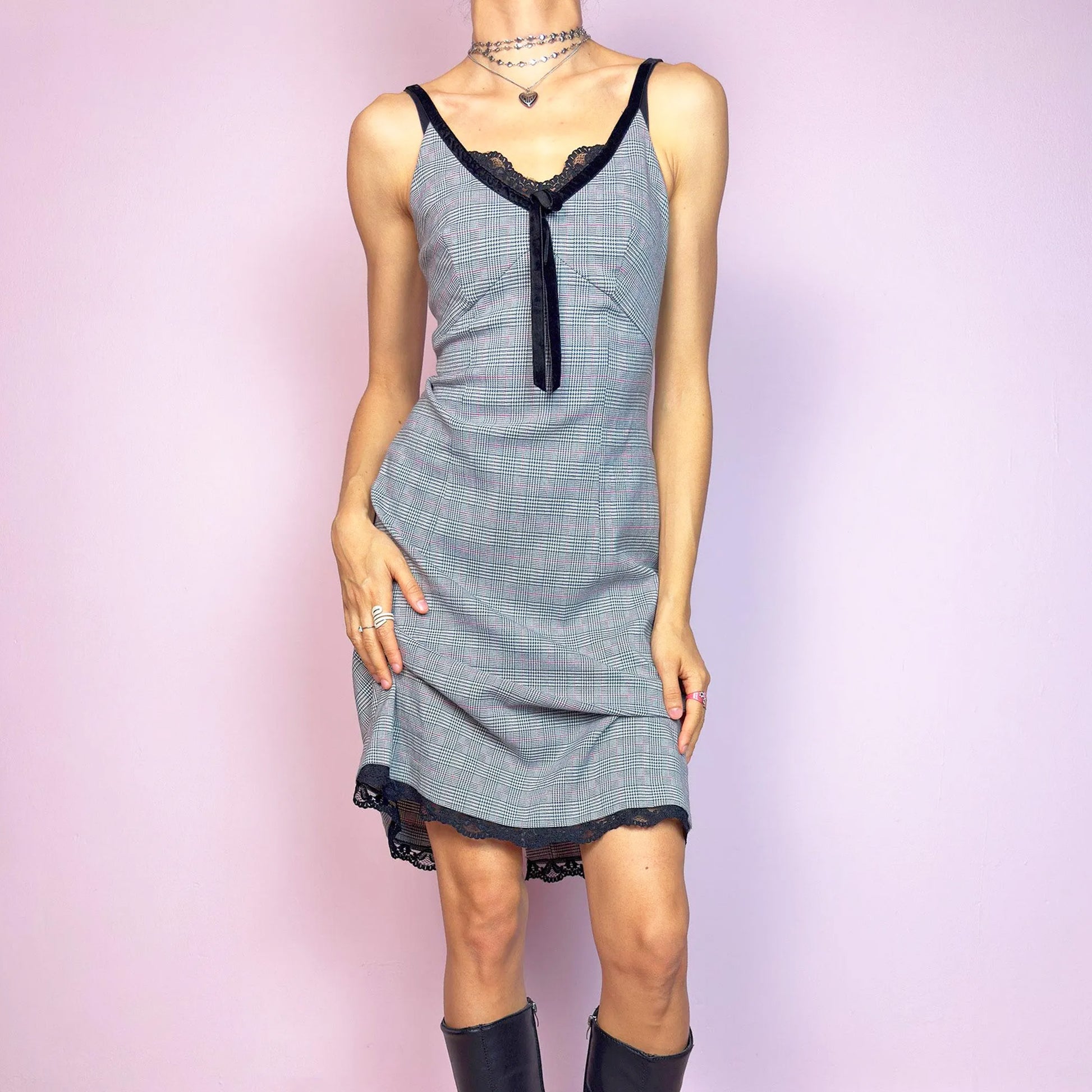 This vintage 2000s slip dress features a gray plaid print with black lace trim and a velvet bow at the bust. It has adjustable straps, a hidden back zipper, mid-length hem, and subtle stretch. The lingerie-inspired cut blends romantic and preppy codes, perfect for summer or layered transitions. A sleek office-core silhouette with soft edge—equal parts elegance and vintage 2000s attitude. Excellent vintage condition.