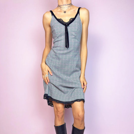 This vintage 2000s slip dress features a gray plaid print with black lace trim and a velvet bow at the bust. It has adjustable straps, a hidden back zipper, mid-length hem, and subtle stretch. The lingerie-inspired cut blends romantic and preppy codes, perfect for summer or layered transitions. A sleek office-core silhouette with soft edge—equal parts elegance and vintage 2000s attitude. Excellent vintage condition.