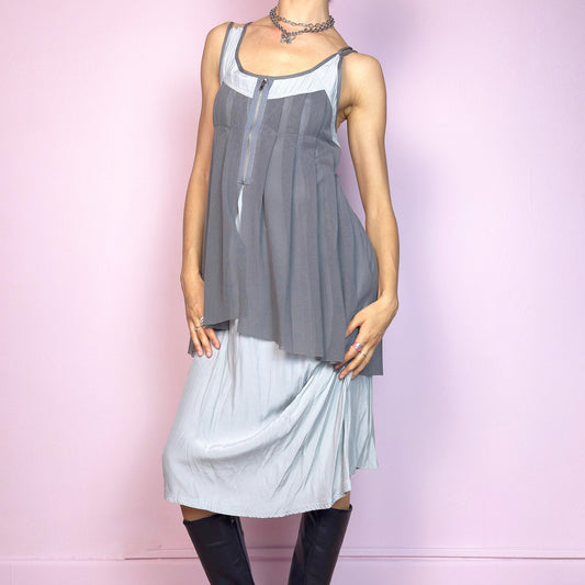 This vintage 2000s midi dress features layered grey tones in mixed textures, including a pleated mesh overlay with faux front zip detail and a side zipper closure. The sleeveless cut and flared asymmetric drape create sculptural movement. Falls below the knee, lightweight, with no stretch. A deconstructed Y2K silhouette—futuristic, quiet, and avant-garde. Perfect for summer days or experimental night looks. Excellent vintage condition.