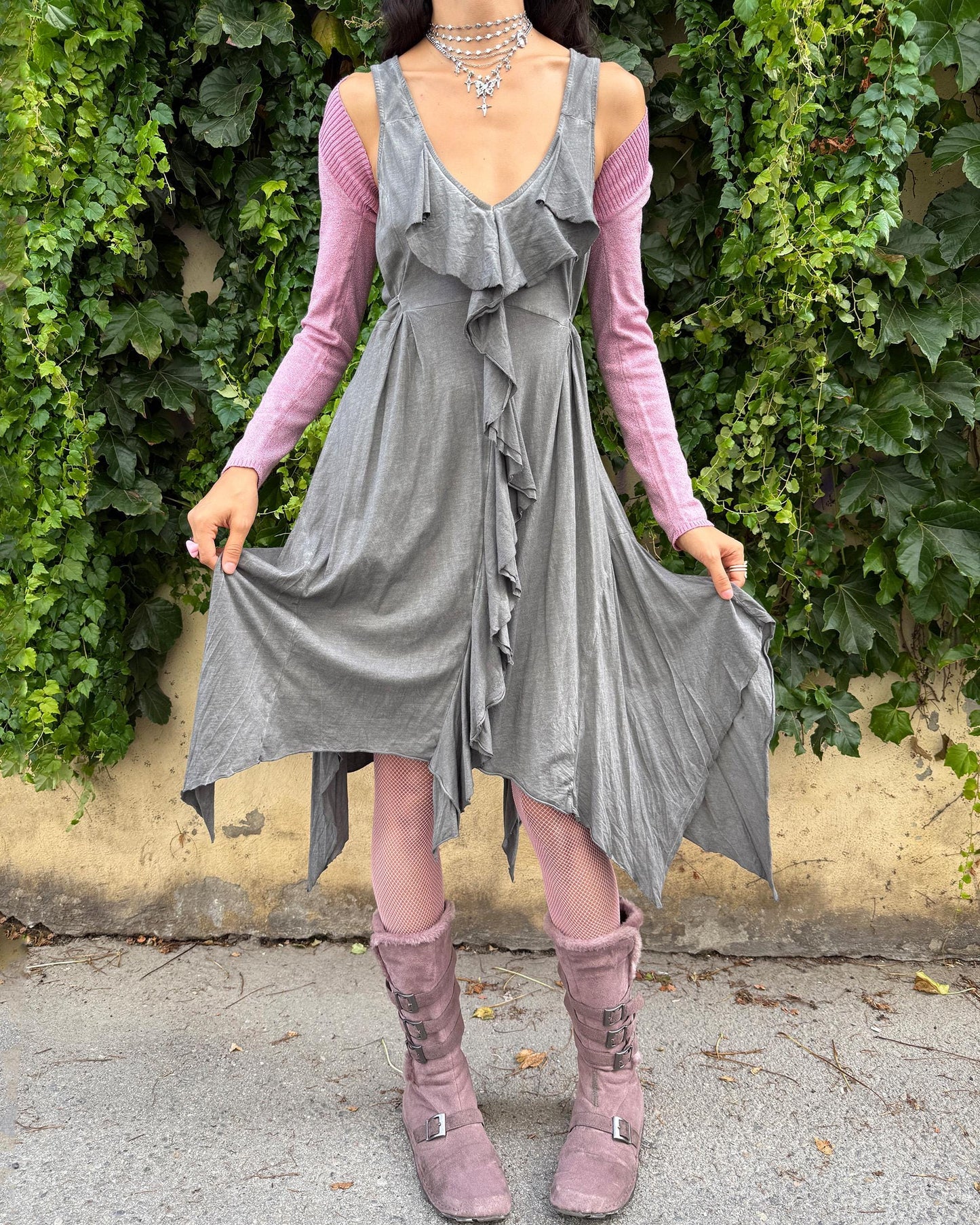 This vintage 2000s gray sleeveless midi dress features a deep V-neckline, cut-out tie back, and cascading ruffles that flow into an asymmetric handkerchief hem. Crafted from soft, stretchy cotton, it embodies whimsical fairycore and deconstructed avant-garde aesthetics in muted tones, perfect for summer layering or artistic styling. Made from 100% cotton fabric. Excellent vintage condition.