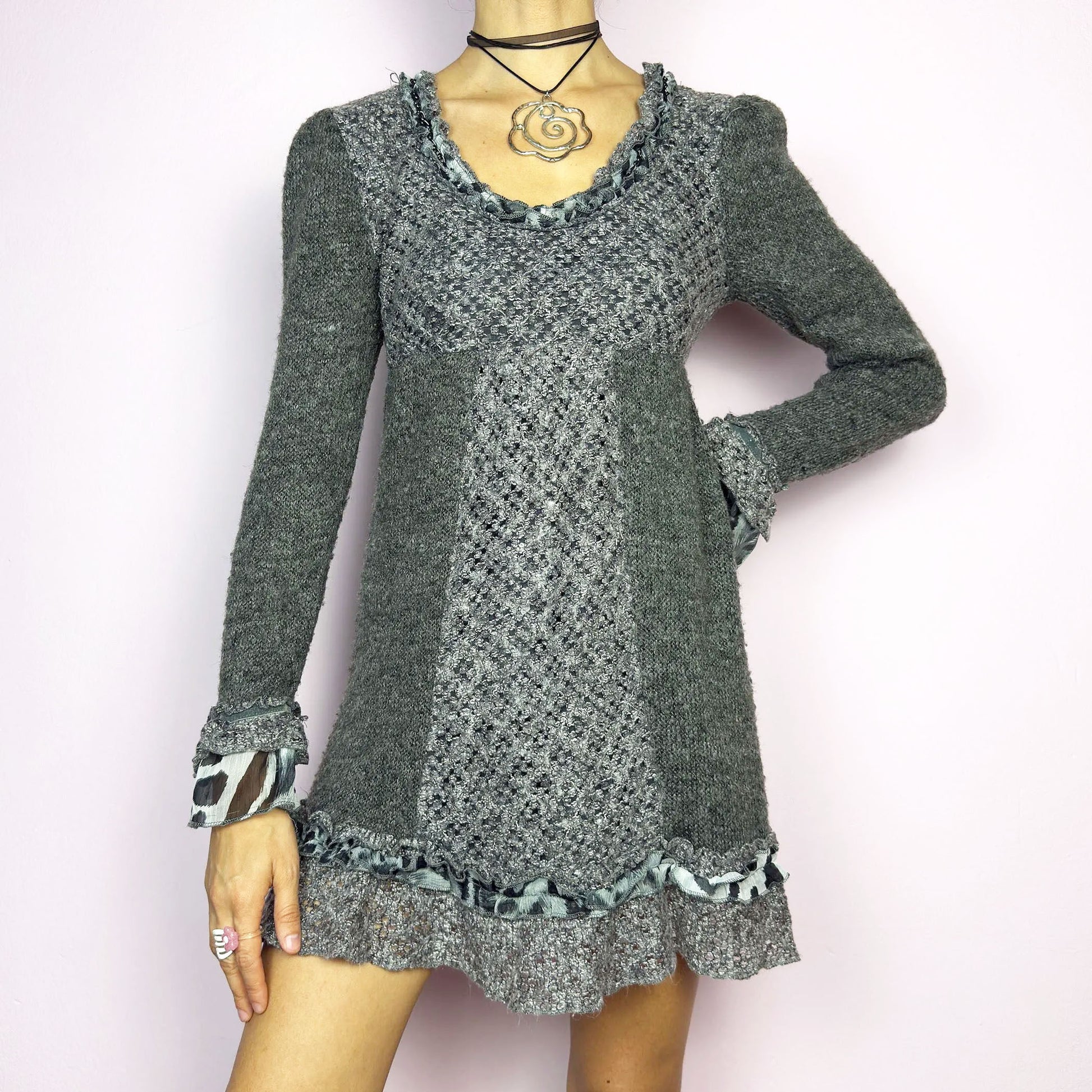 The Y2K Gray Knit Mini Dress is a vintage 2000s piece featuring a patchwork knit design with ruffle trim details. With a fitted bust and flared hem, this dress has a romantic and whimsical aesthetic. The long sleeves add a cozy touch. Perfect for a dreamy, fairycore-inspired outfit.