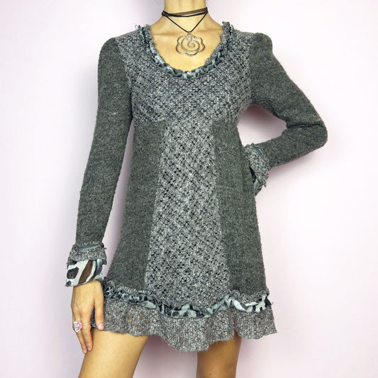 The Y2K Gray Knit Mini Dress is a vintage 2000s piece featuring a patchwork knit design with ruffle trim details. With a fitted bust and flared hem, this dress has a romantic and whimsical aesthetic. The long sleeves add a cozy touch. Perfect for a dreamy, fairycore-inspired outfit.