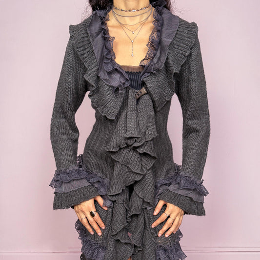 Romantic vintage 2000s gray longline cardigan with dramatic ruffle neckline and lace details. Features bell sleeves with ruffle cuffs, toggle front closure, and asymmetric pointy hem. Whimsical fairycore silhouette with dark baroque rococo style. Stretchy fabric for cozy winter layering. Made from acrylic mohair wool blend. Excellent vintage condition.