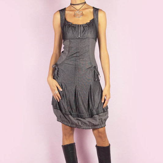 The Y2K Gray Bubble Mini Dress is a vintage 2000s piece featuring a striped, stretchy fabric with a structured bodice and a front zipper detail. The design includes pockets with drawstrings and the bubble hemline adds volume and playfulness. Perfect for night outings or unique casual styles.
