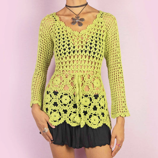 The Y2K Green Crochet Sweater is a vintage 2000s top featuring an open-knit, intricate crochet pattern and a tie-front detail at the waist. A perfect layering piece for a spring or summer casual or beach look.