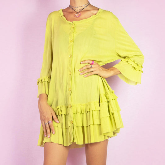 The Y2K Green Mesh Ruffle Blouse is a vintage 2000s top featuring a semi-sheer mesh fabric and a button-down front. This blouse has ruffle details along the hem and sleeves, with three-quarter length sleeves. Perfect for a summer outfit or a fun party look.
