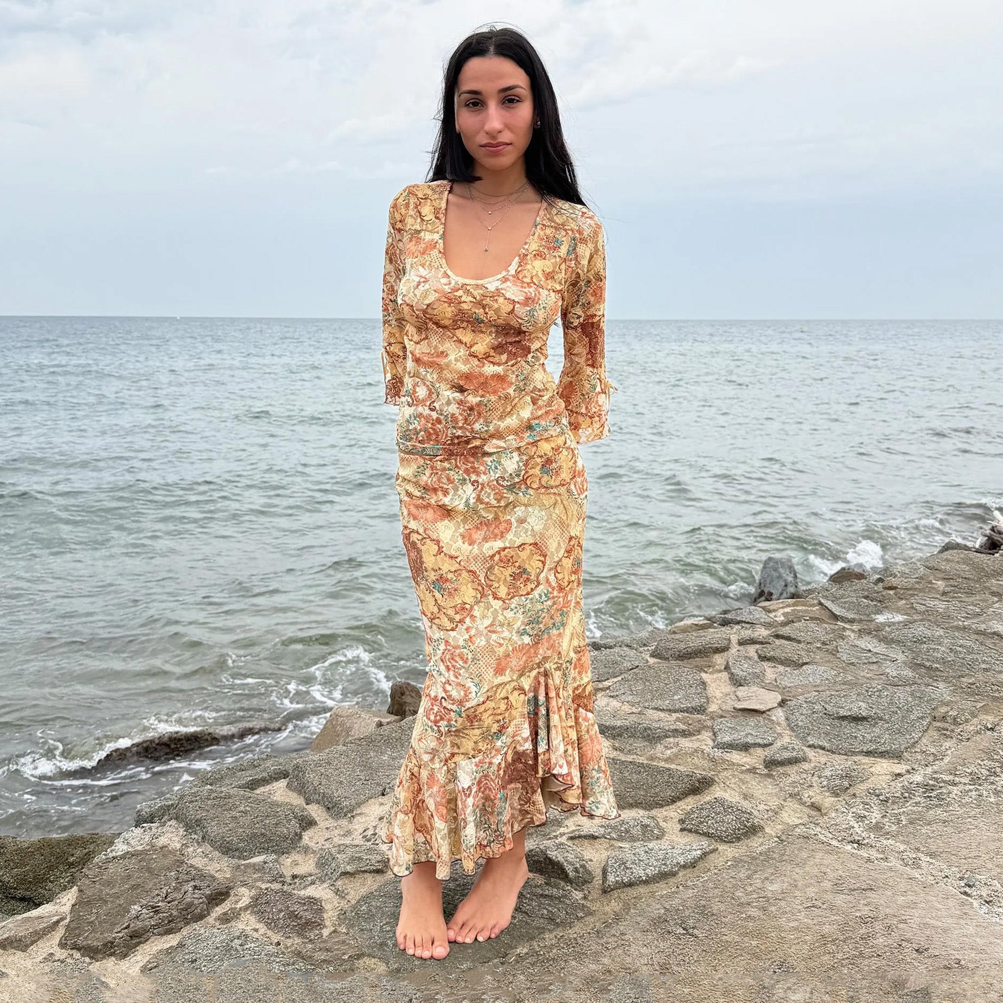 Vintage 2000s cream-beige floral lace mesh two-piece set with brown and blue accents. Features an asymmetric midi skirt with flowing ruffle hem and matching semi-sheer scoop neck top with three-quarter tie bell sleeves. Ideal for parties, festivals, and seaside escapes. Made in Spain from polyester stretch mesh. Excellent vintage condition.