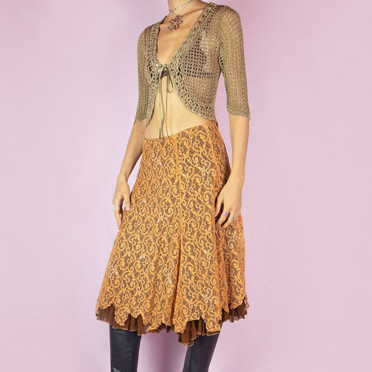 This vintage 2000s lace skirt is a layered evening statement in burnt orange and chocolate brown. Features a sheer embroidered lace overlay embellished with delicate beadwork, pleated brown underlayer, and soft handkerchief hem for added movement. Mid-length with a flattering flare and structured with a back zipper closure. Perfect for autumn events, bohemian party looks, or romantic wardrobes.
