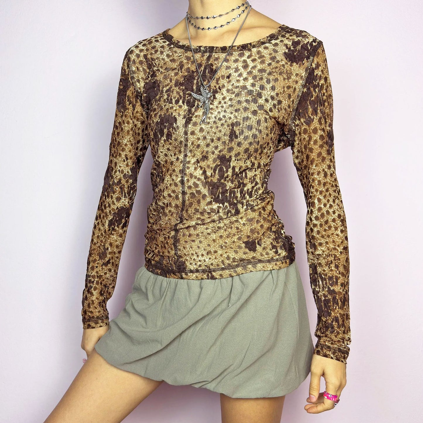 The Y2K Animal Print Mesh Top is a vintage 2000s sheer long-sleeve top featuring a bold cheetah-inspired print in earthy brown tones. Designed with visible contrast stitching, and a soft stretch mesh fabric, this piece is perfect for casual or night-out looks.