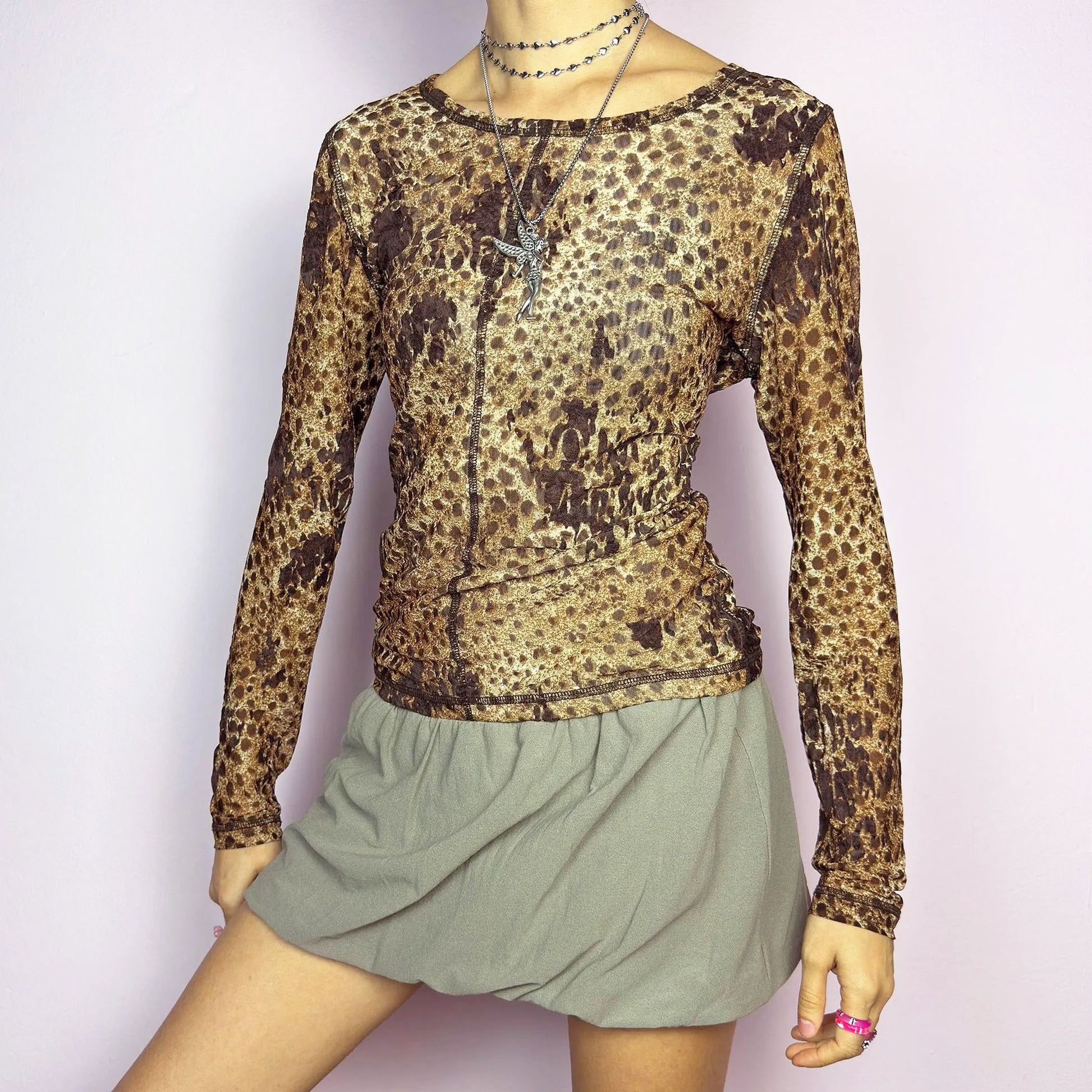 The Y2K Animal Print Mesh Top is a vintage 2000s sheer long-sleeve top featuring a bold cheetah-inspired print in earthy brown tones. Designed with visible contrast stitching, and a soft stretch mesh fabric, this piece is perfect for casual or night-out looks.