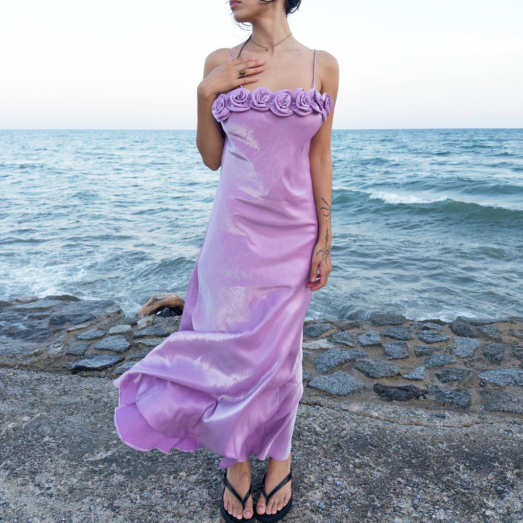 The vintage 2000s pastel lilac slip dress is a French-made fantasy with sculptural rosette appliqué along the bust. Its iridescent finish and fluid midi length evoke dreamy softness, perfect for proms, summer weddings, or romantic evenings. The silhouette captures fairytale allure with quiet glamour. A romantic Y2K archive crafted from a shimmering non-stretch polyester blend fabric. Excellent vintage condition.